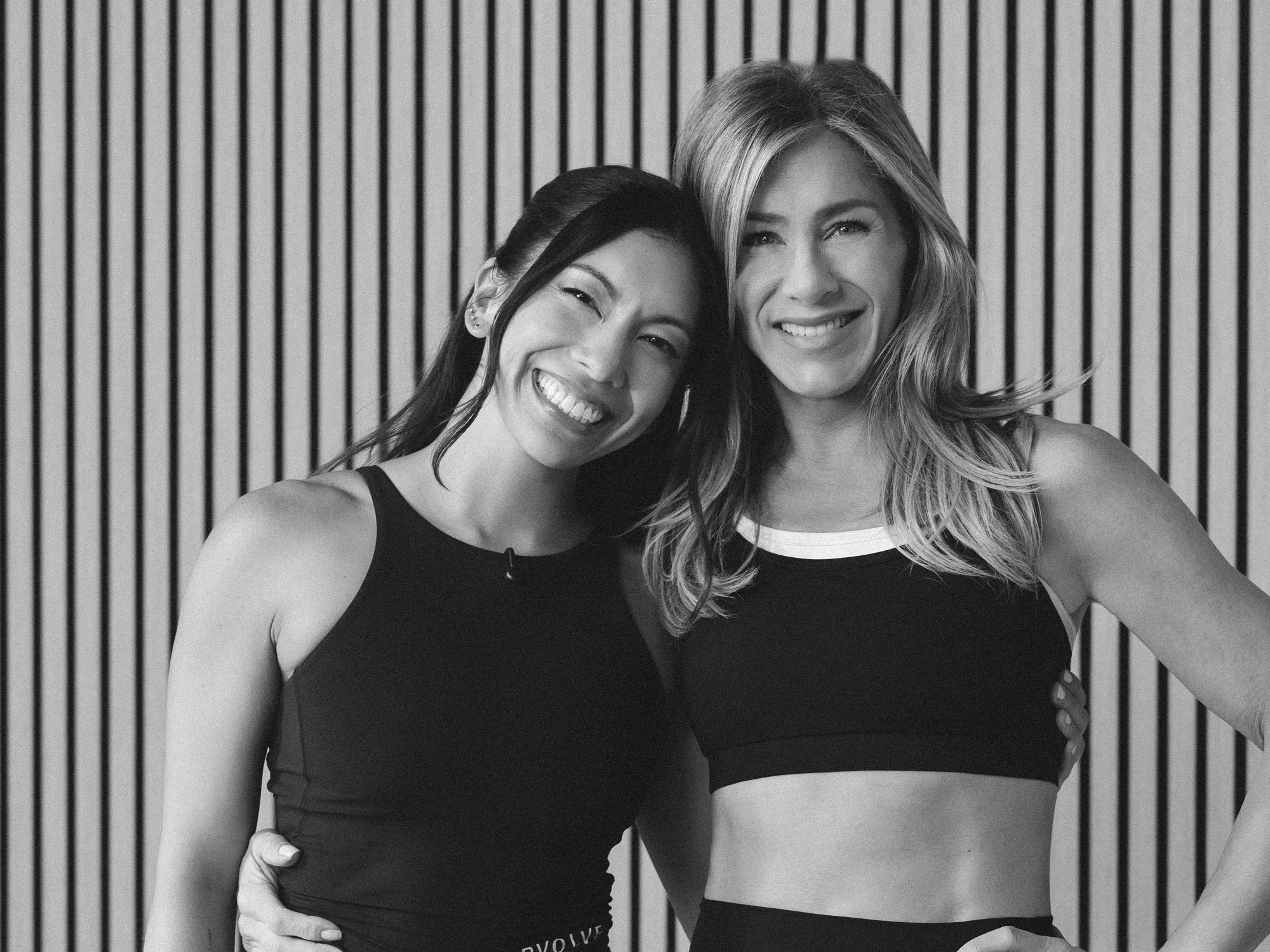 Personal trainer Dani Coleman posing for a photo with actress Jennifer Aniston in black and white on a striped background