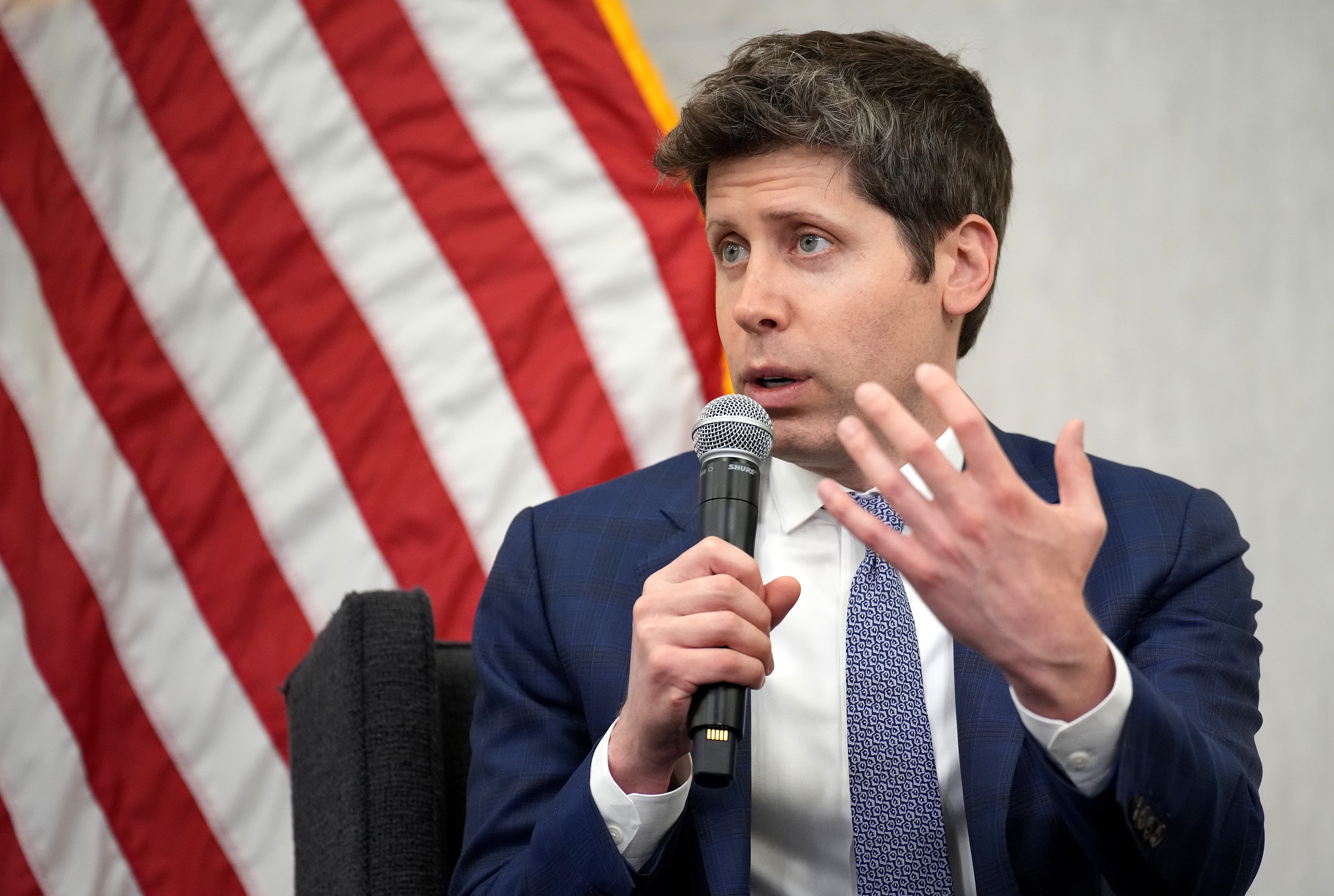Sam Altman is holding a microphone and speaking.