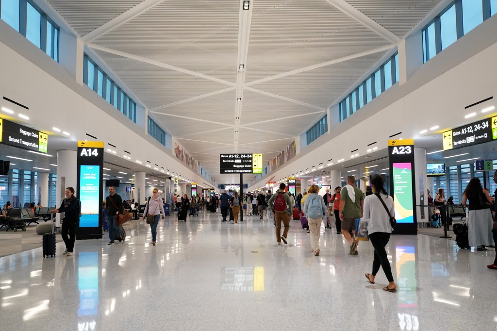 Interior view of the newly opened Terminal A of Newark Liberty International Airport, with travelers walking through the concourse.