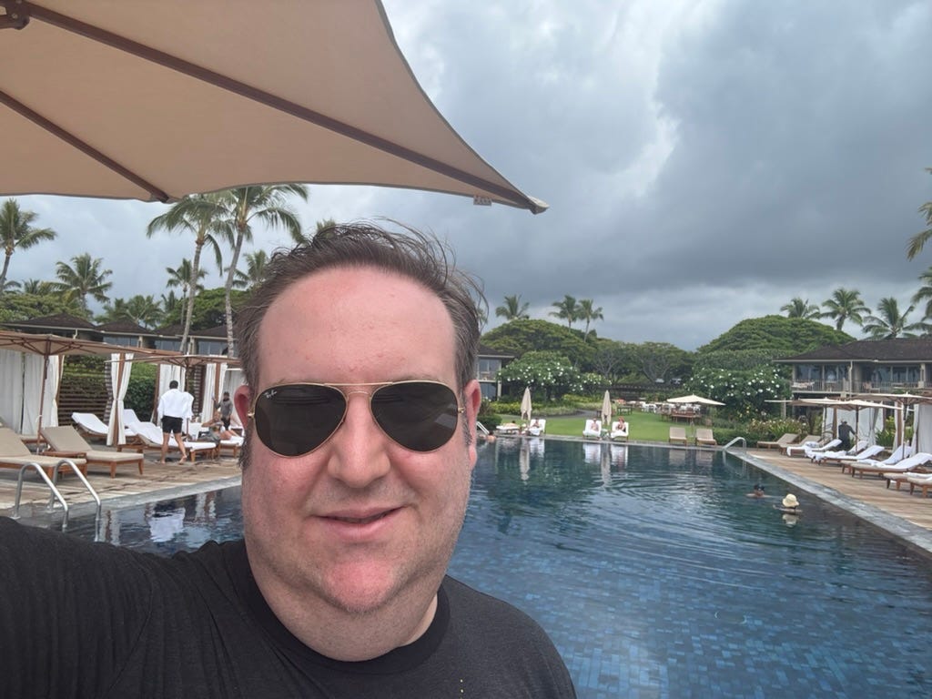 Author David Morris with sunglasses on smiling in front of pool