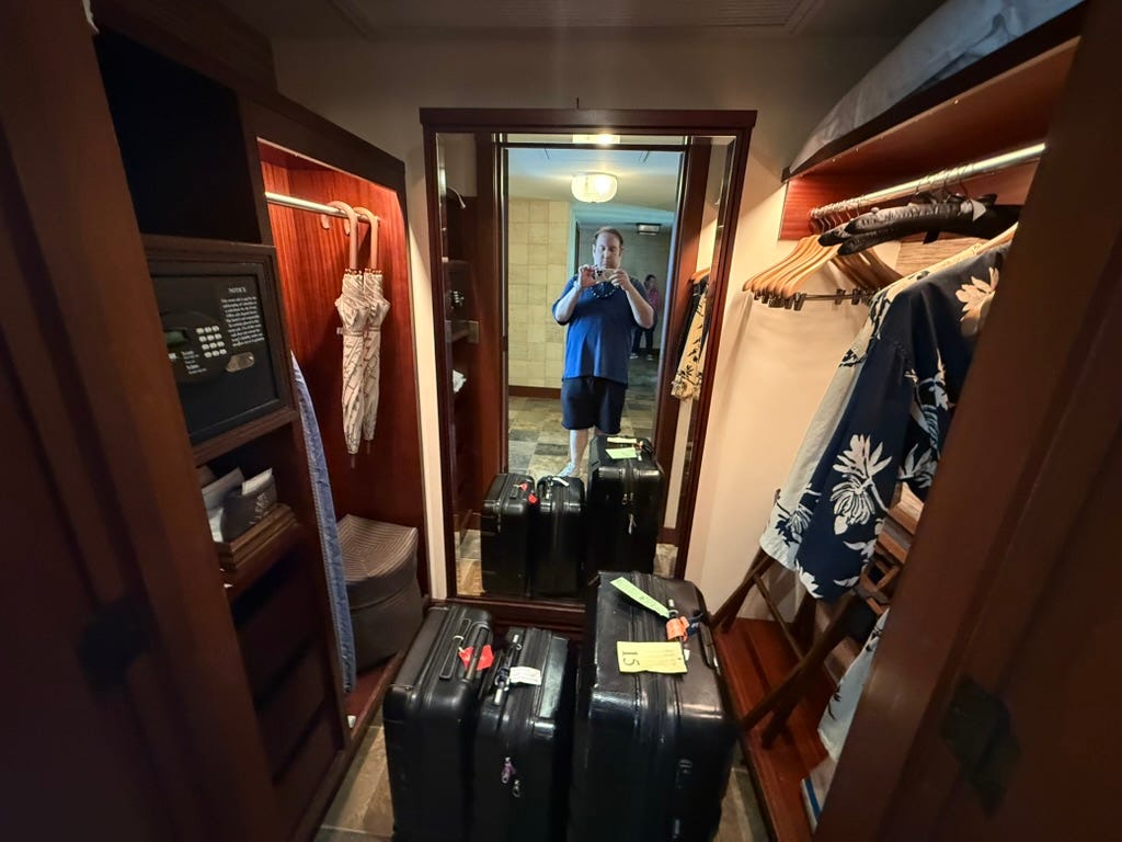 Author David Morris taking selfie in mirror of walk-in closet with suitaces inside