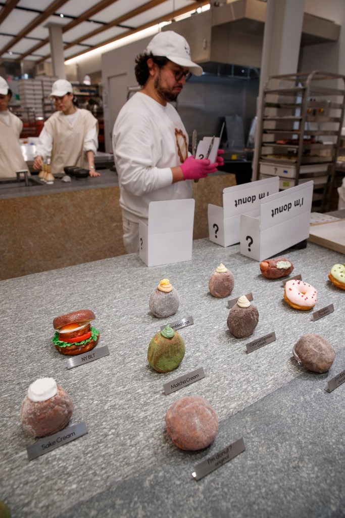 Donuts on display at I'm Donut, with flavors like NY BLT, Sake Cream, Matcha Cream, and Caramel Espresso Cream.