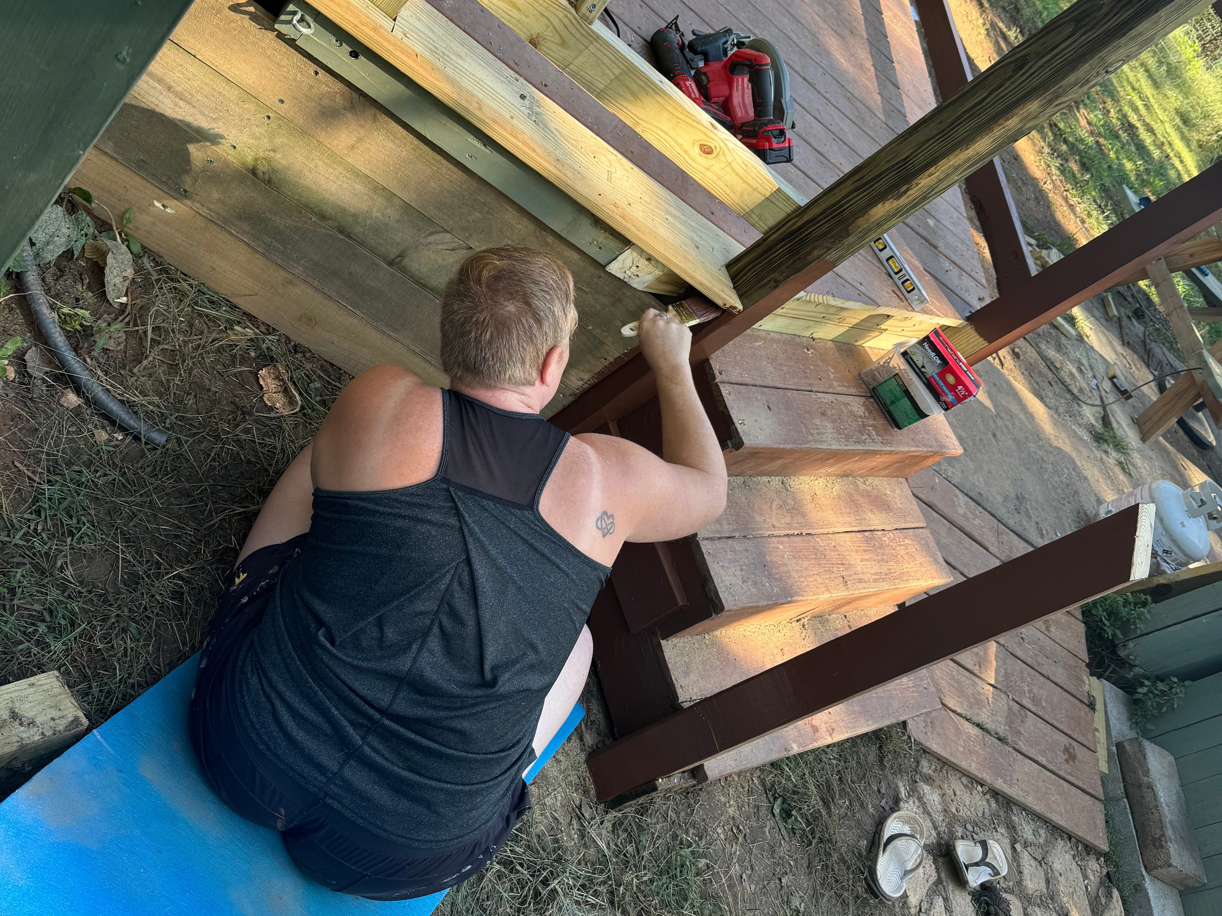A woman painting the deck of a tiny home