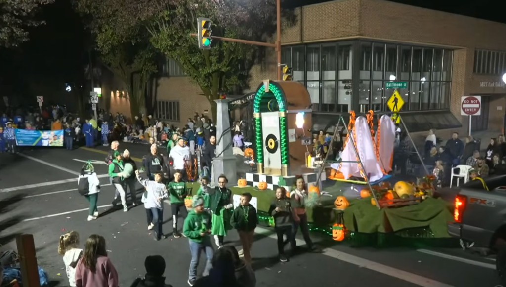 A Halloween parade float featuring a tombstone with a German phrase and a jukebox.