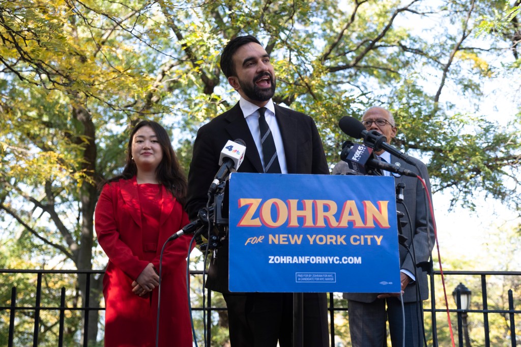 New York State Representative and Mayoral Candidate Zohran Mamdani speaking at a podium with City Council member Julie Won and New York State Senator Robert Jackson.