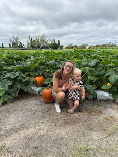 The author poses with her child in a pumpkin patch.
