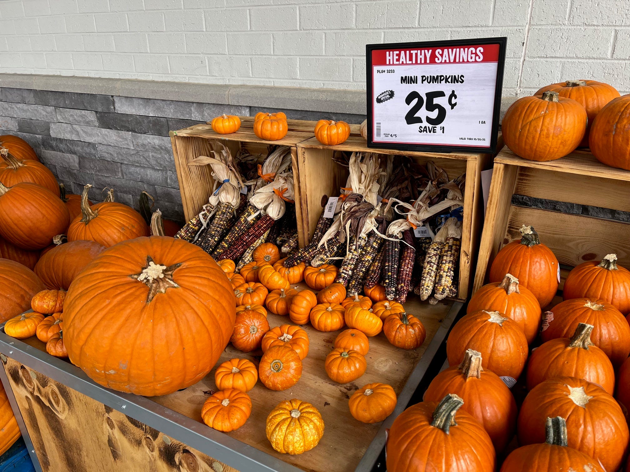 Pumpkins and dried ears of corn sit in a display outside Sprouts Farmers Market