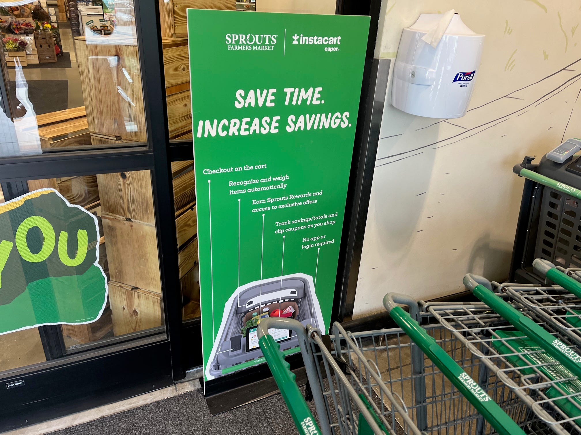 A sign at Sprouts promotes Instacart's Caper shopping carts with the slogan