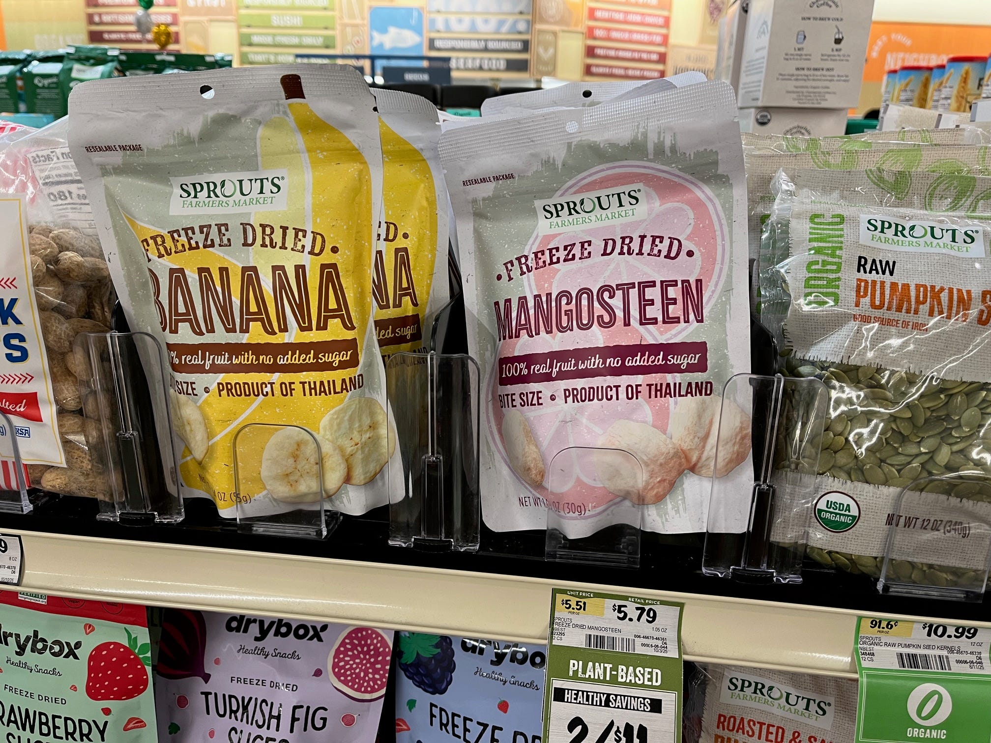Packages of dried bananas and mangosteen sit on a shelf at Sprouts