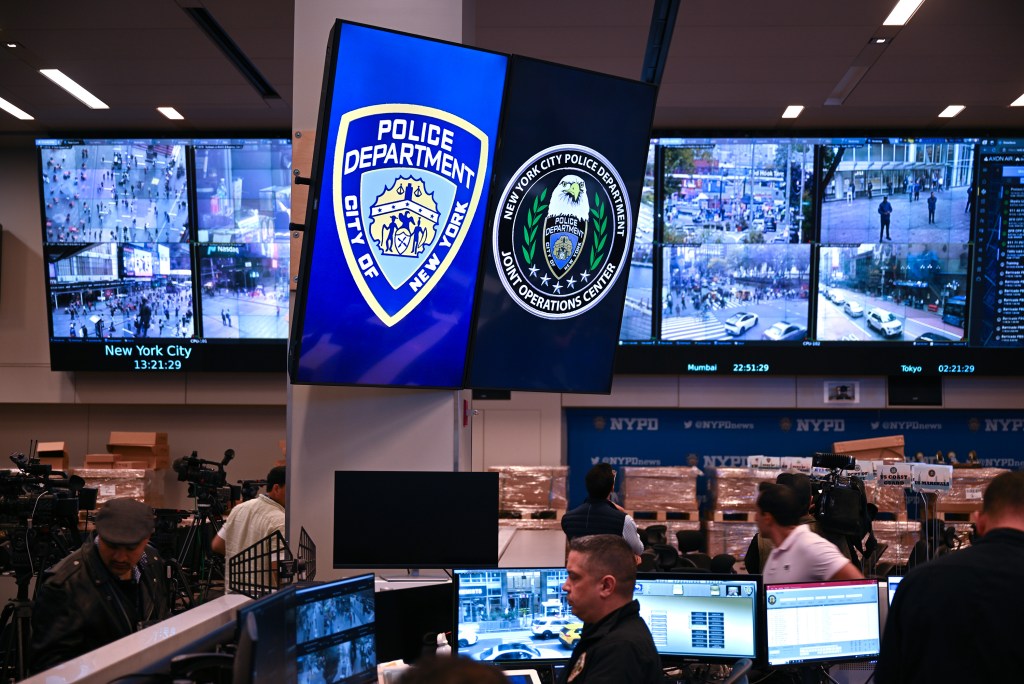 NYPD Joint Operations Center with multiple screens displaying surveillance footage and two large seals for the NYPD and Joint Operations Center.