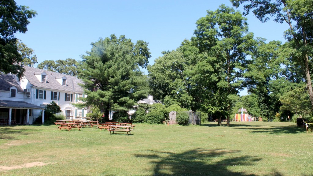 The grounds of Sweetbriar Nature Center, with a white building on the left and a grassy area with picnic tables.