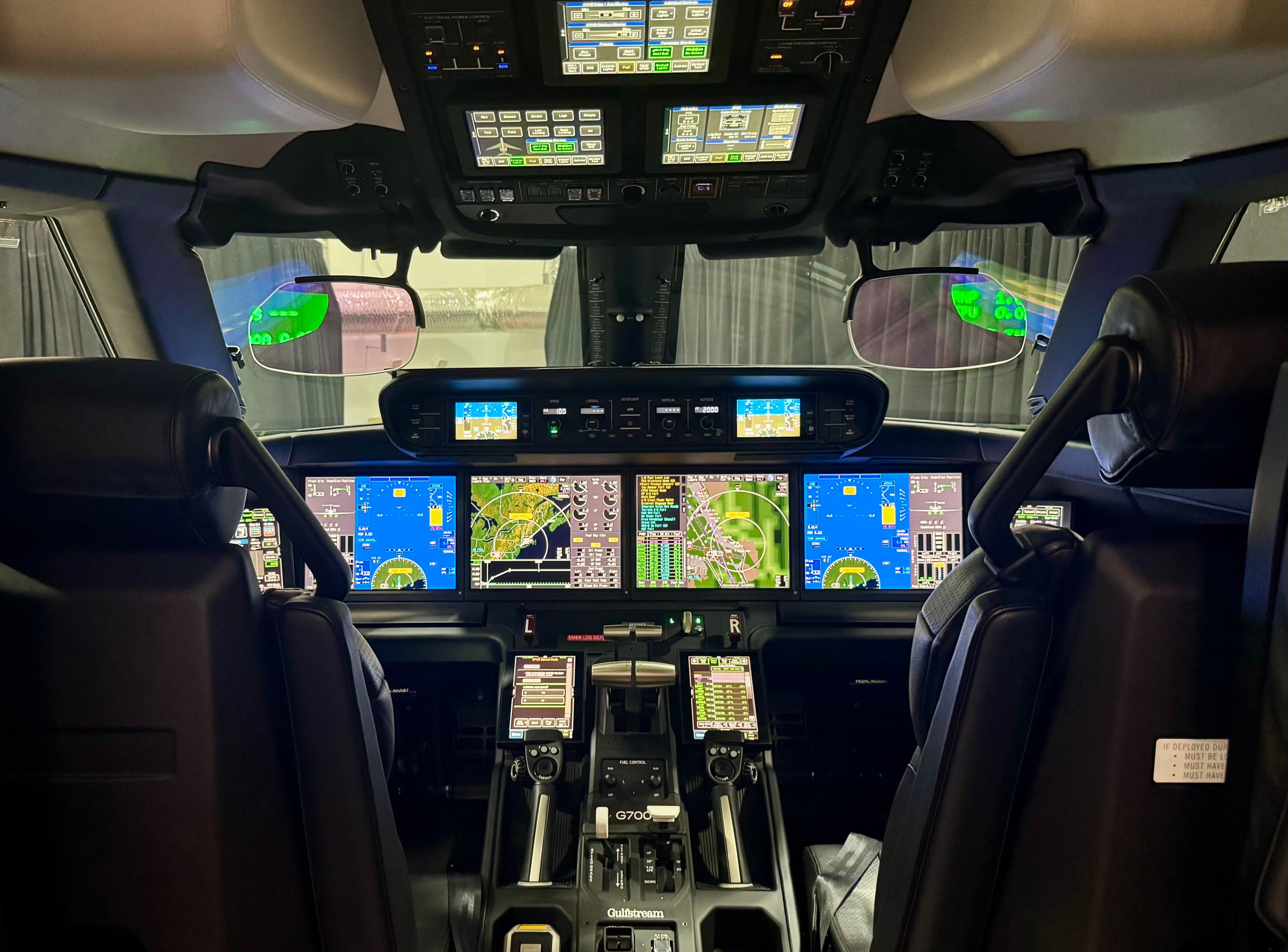 Inside the G700 cockpit with screens and buttons lit up.