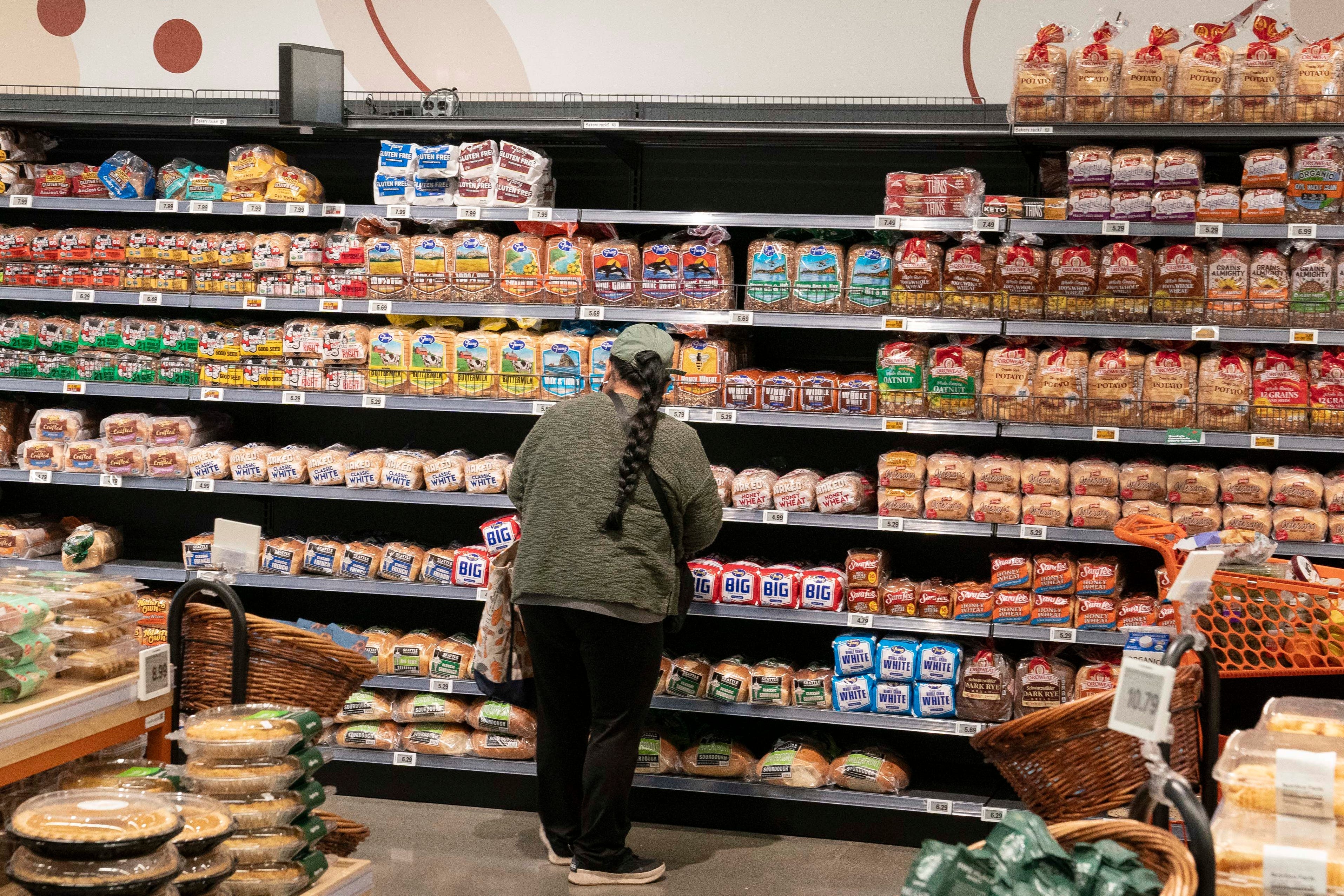 A shopper stands in the bread aisle at a supermarket.