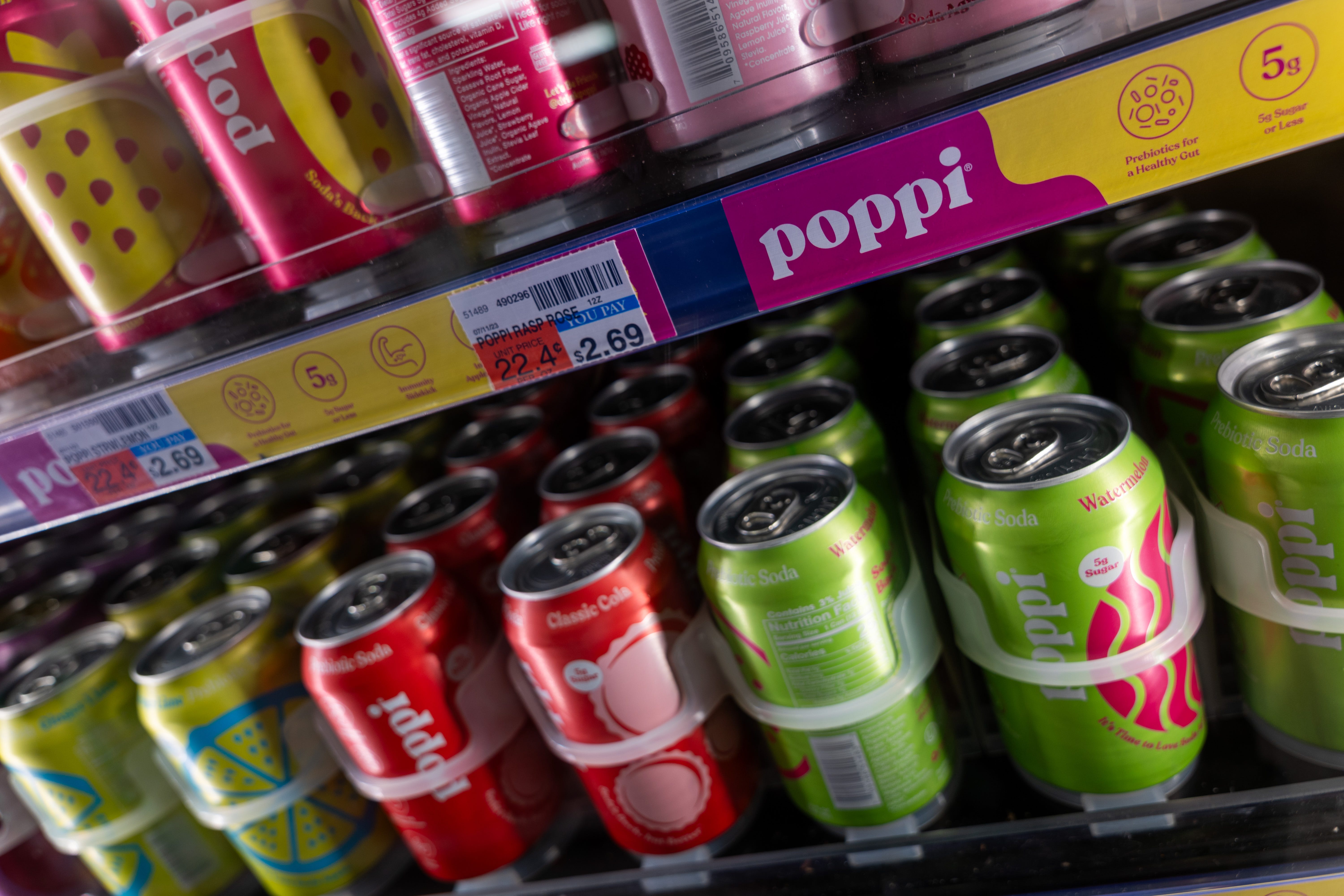 Poppi soda cans in a supermarket refrigerator.