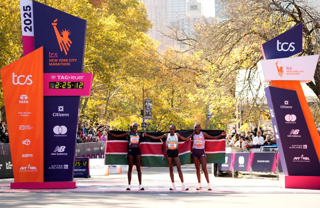 Hellen Obiri celebrates her win at the TCS New York City Marathon with Sharon Lokedi and Sheila Chepkirui, holding the Kenyan flag.