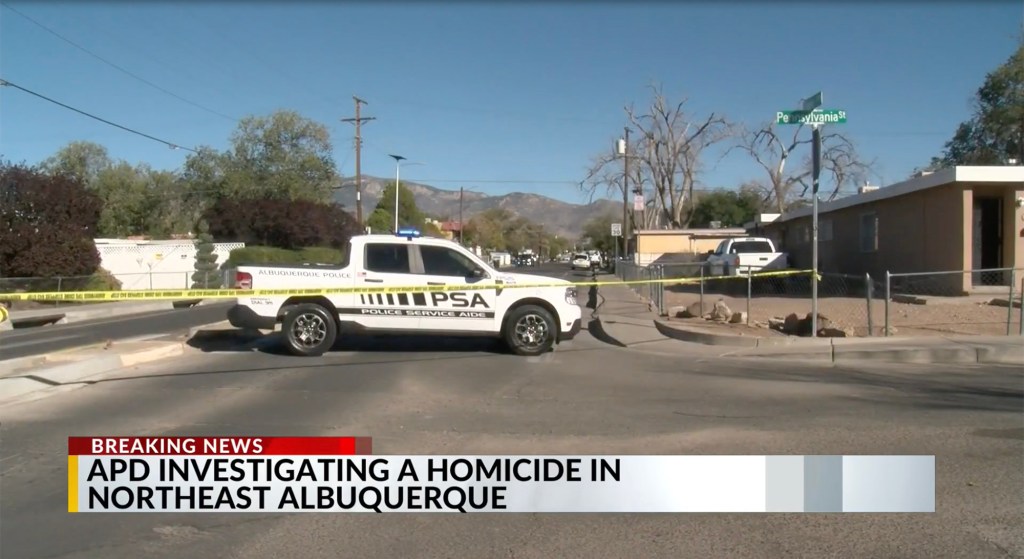 A police vehicle at a crime scene blocked off with yellow tape at the intersection of Pennsylvania St. and another street in Albuquerque.