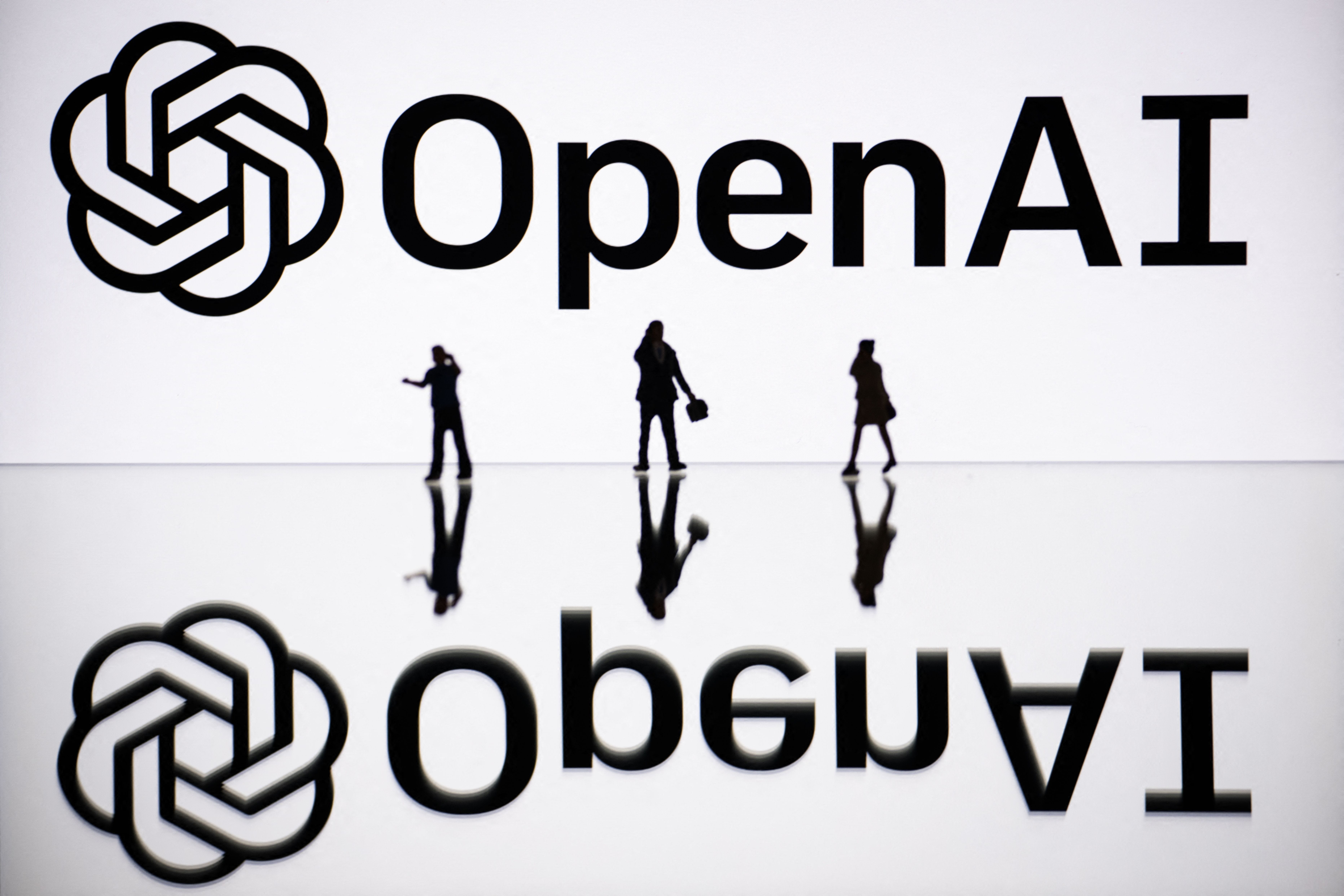 People walking by screen showing OpenAI logo in France in 2023.