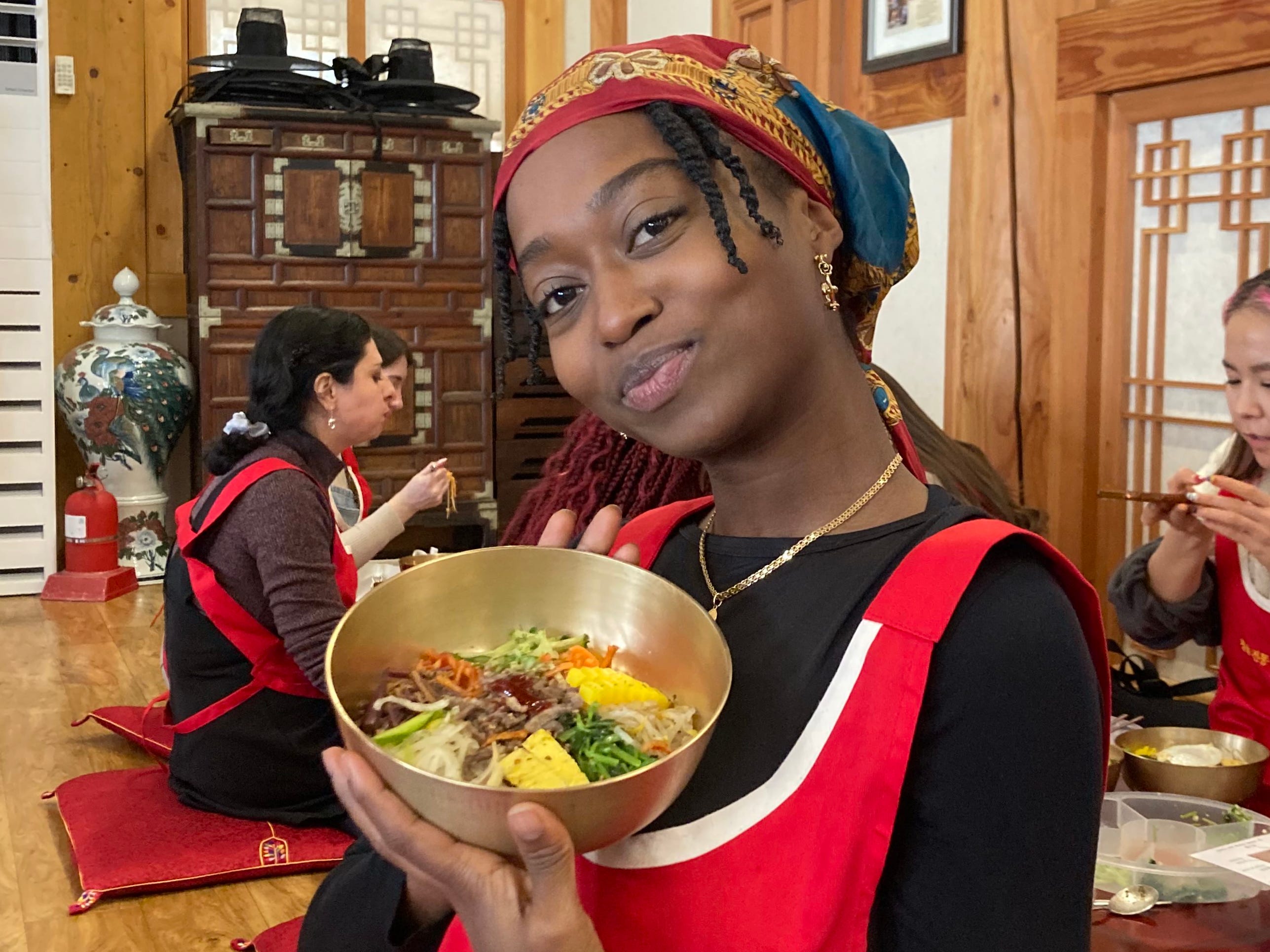A woman posing with a bowl of bibimbap that she made.