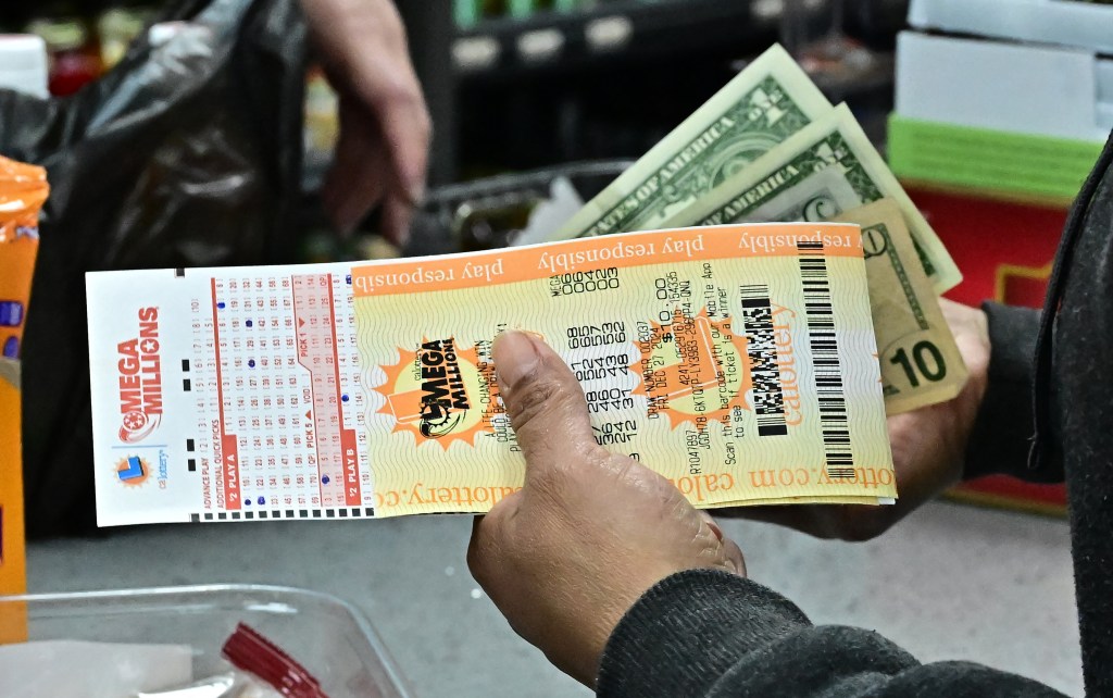 A person holding Mega Millions lottery tickets and cash.