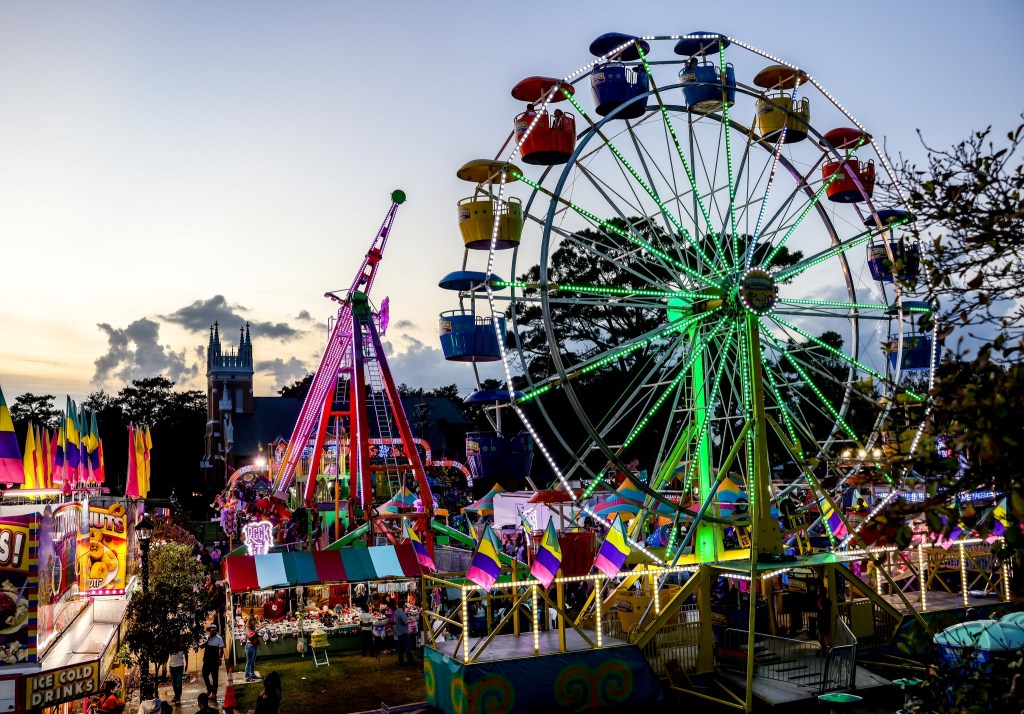 A ferris wheel and other rides lit up at night at the Harvest Festival on False River.