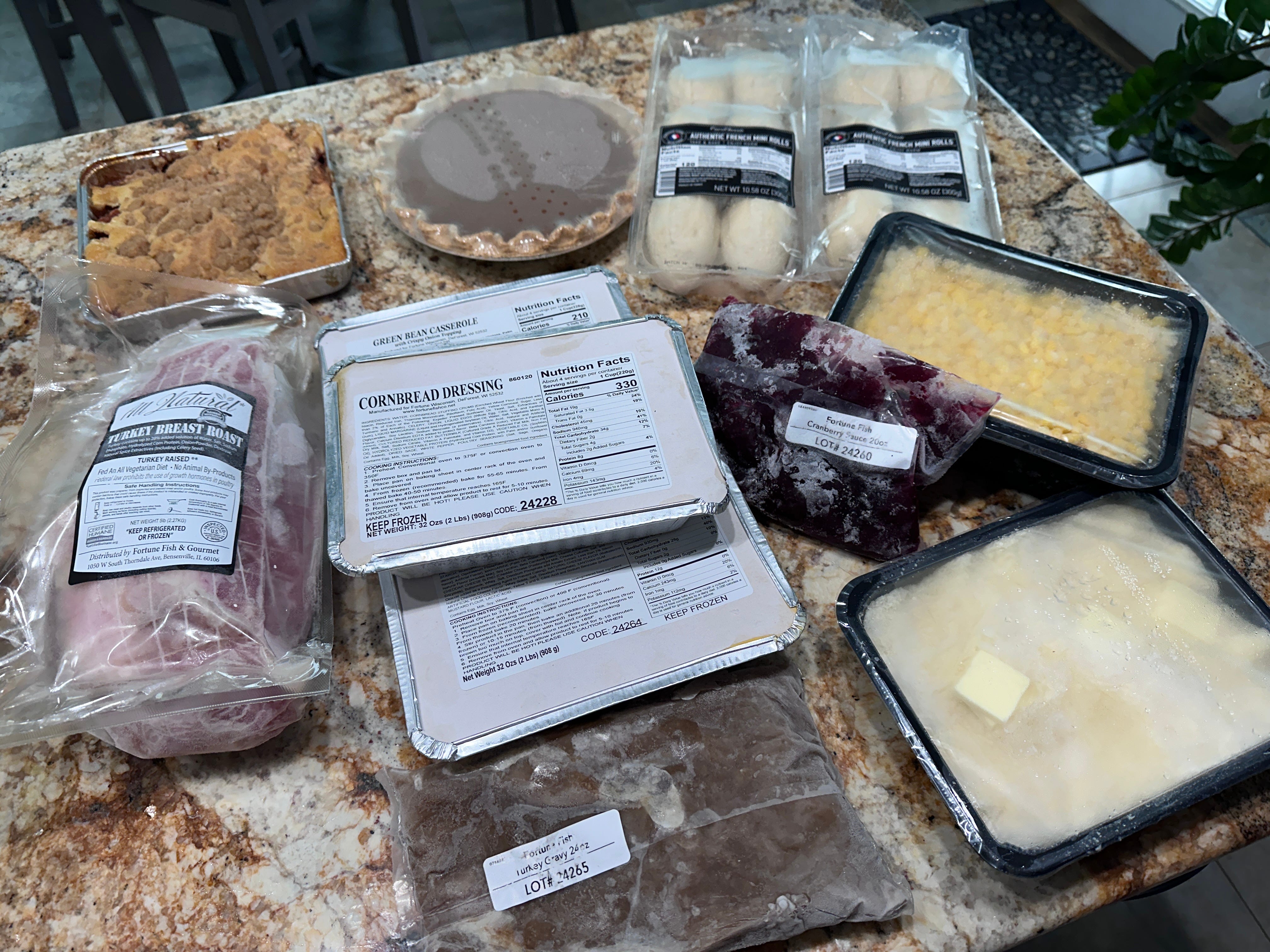 Spread of packaged Thanksgiving food on counter with instructions taped to them