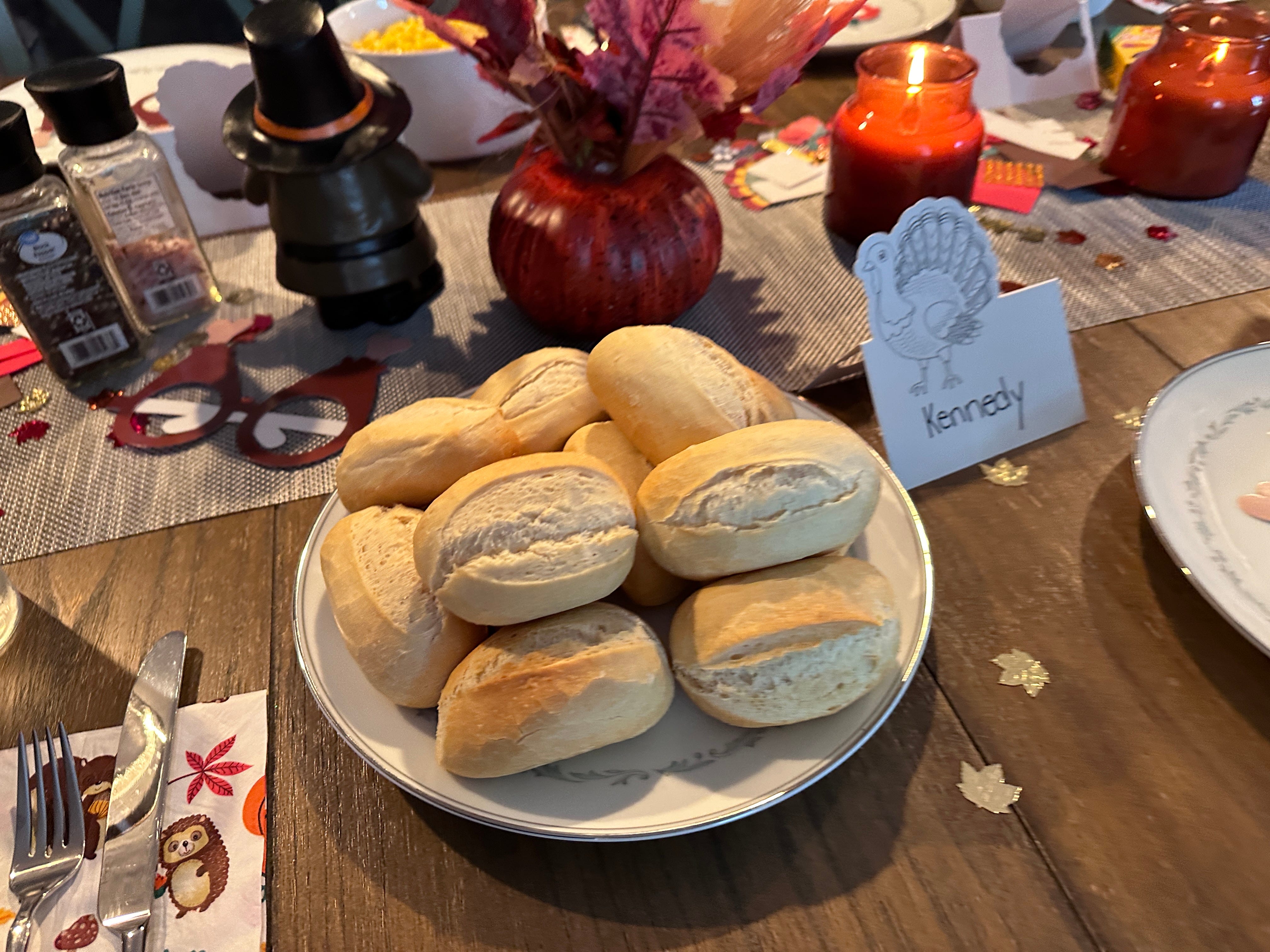 Rolls on a plate on a table set for Thanksgiving.