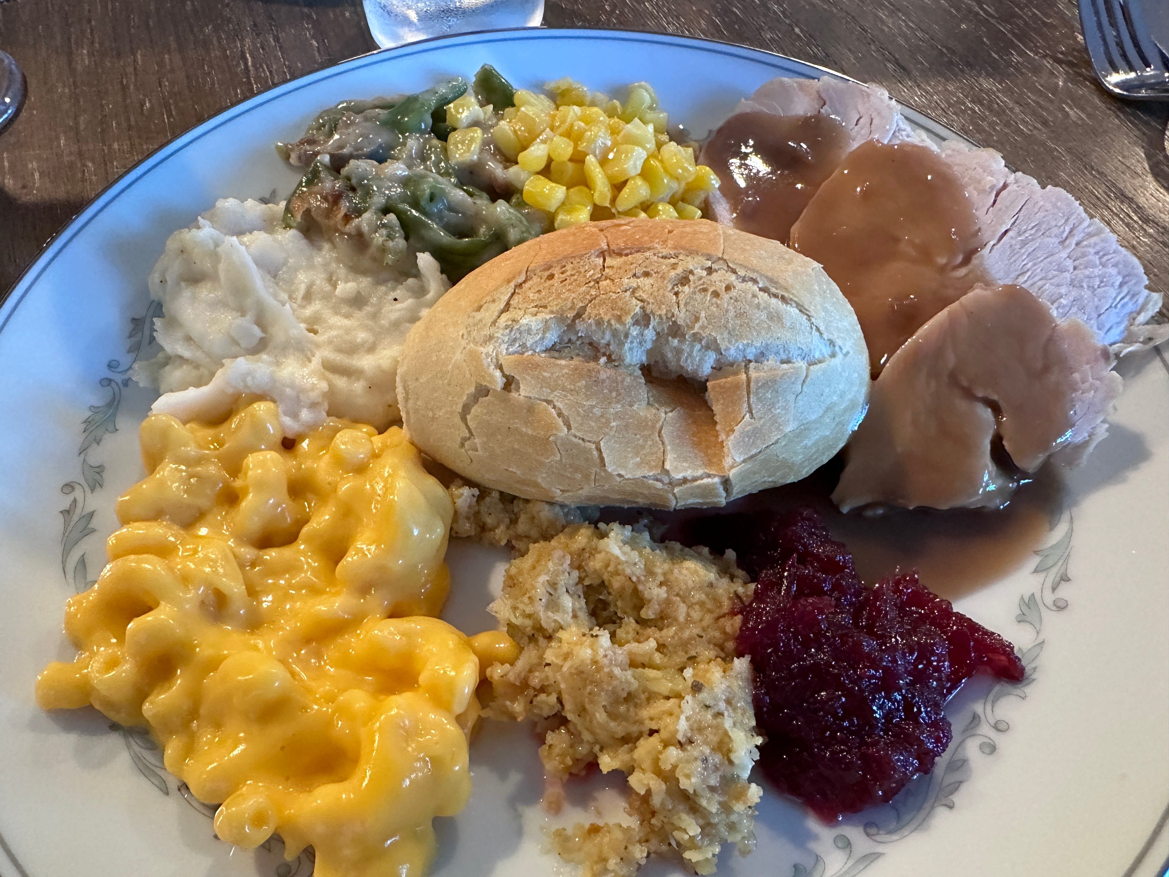 Plate with roll, mac and cheese, turkey, stuffing, cranberry sauce, mashed potatoes, green-bean casserole