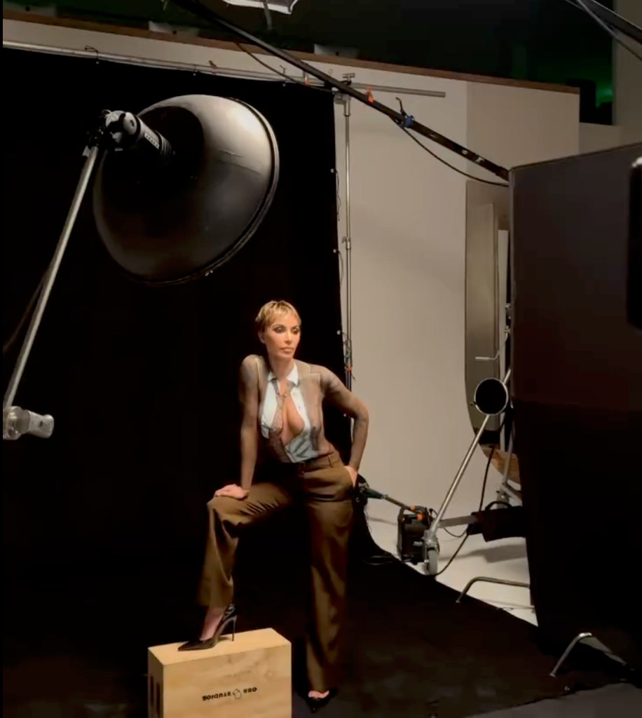 Kim Kardashian poses in body paint that resembles a shirt and trousers in a photoshoot.