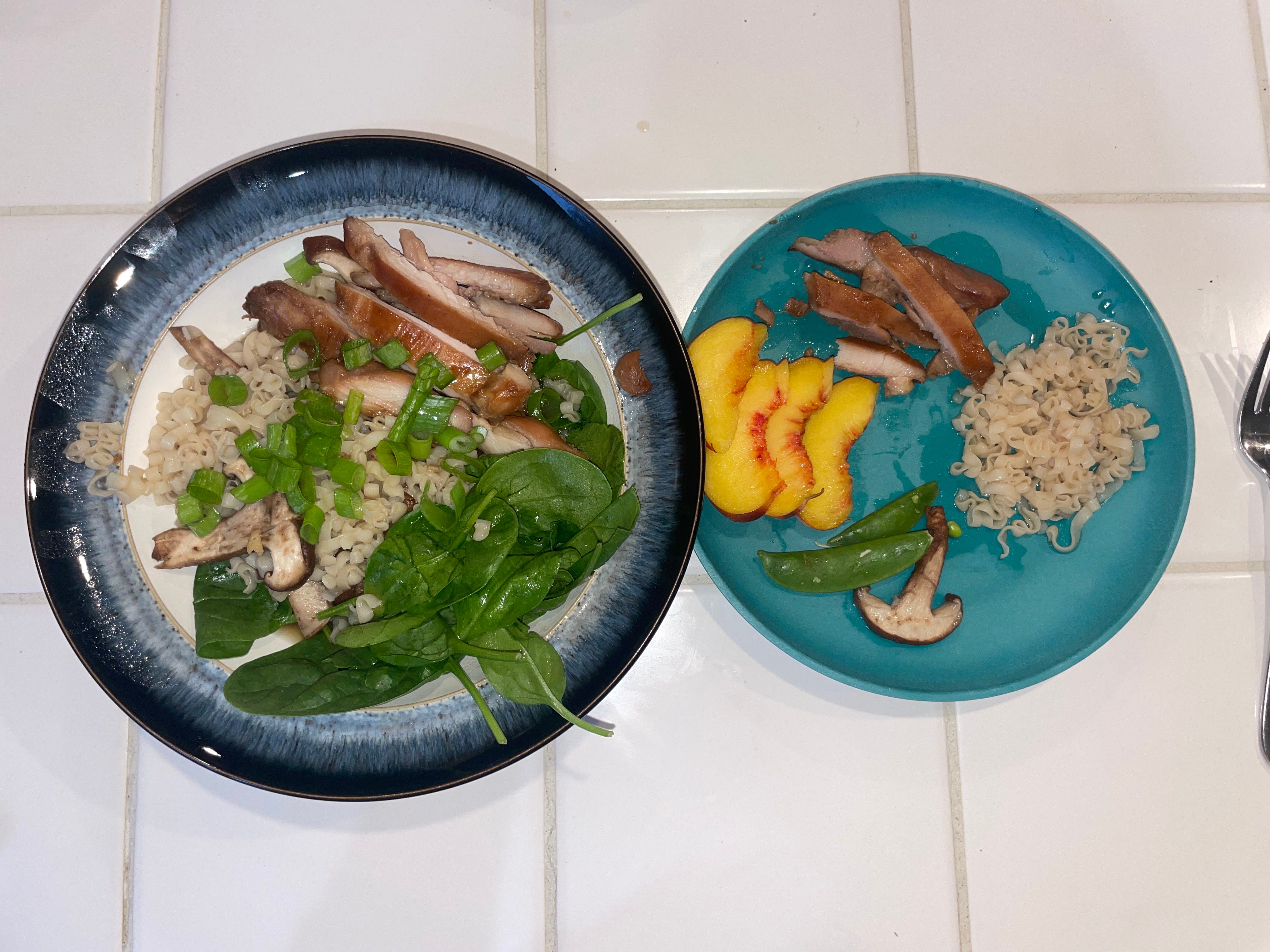 Ramen in a bowl next to bowl with ramen noddles, fruit, meat