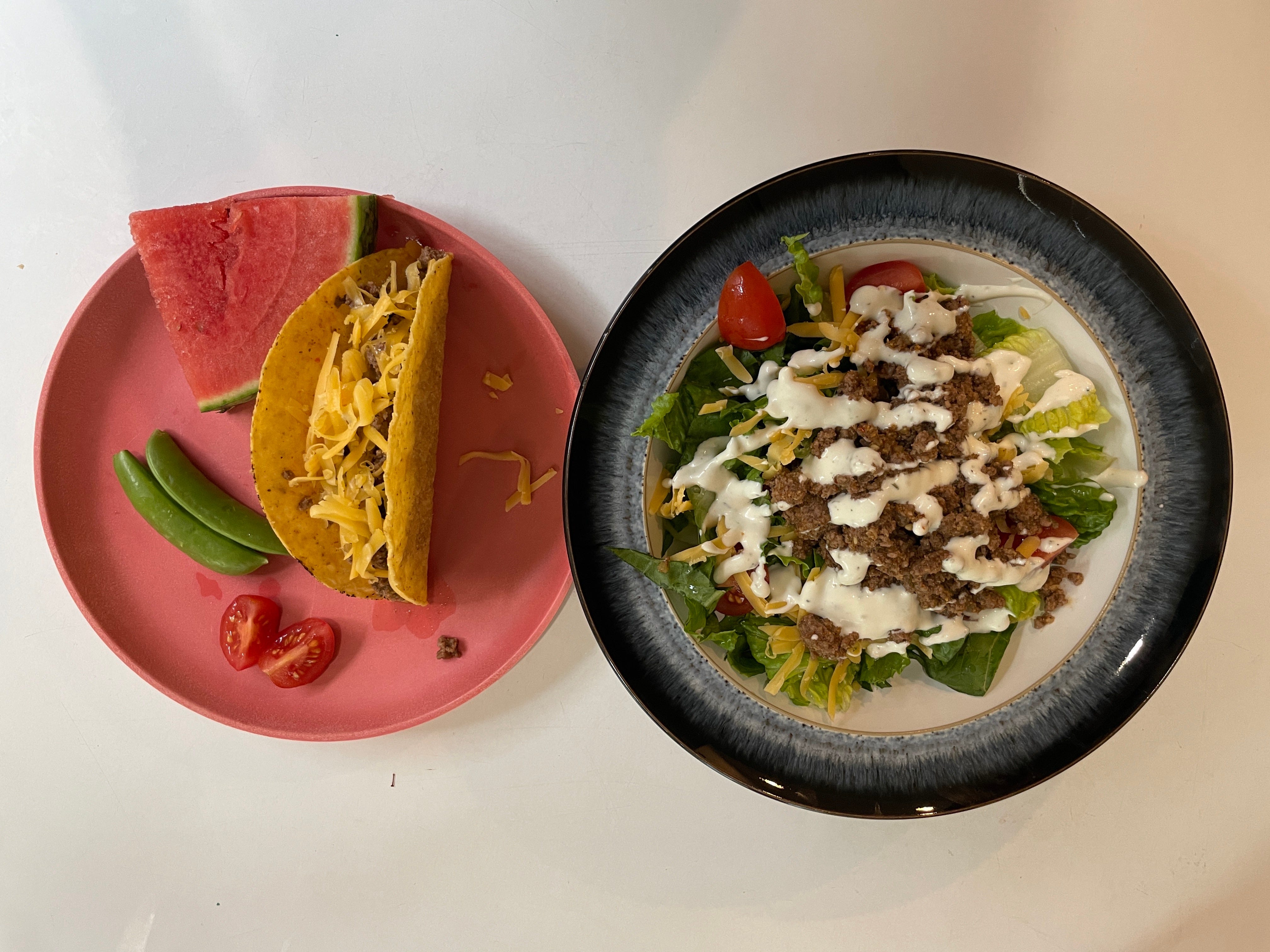 plate with a hard-shell taco and one with a bed of lettuce with neat, cheese