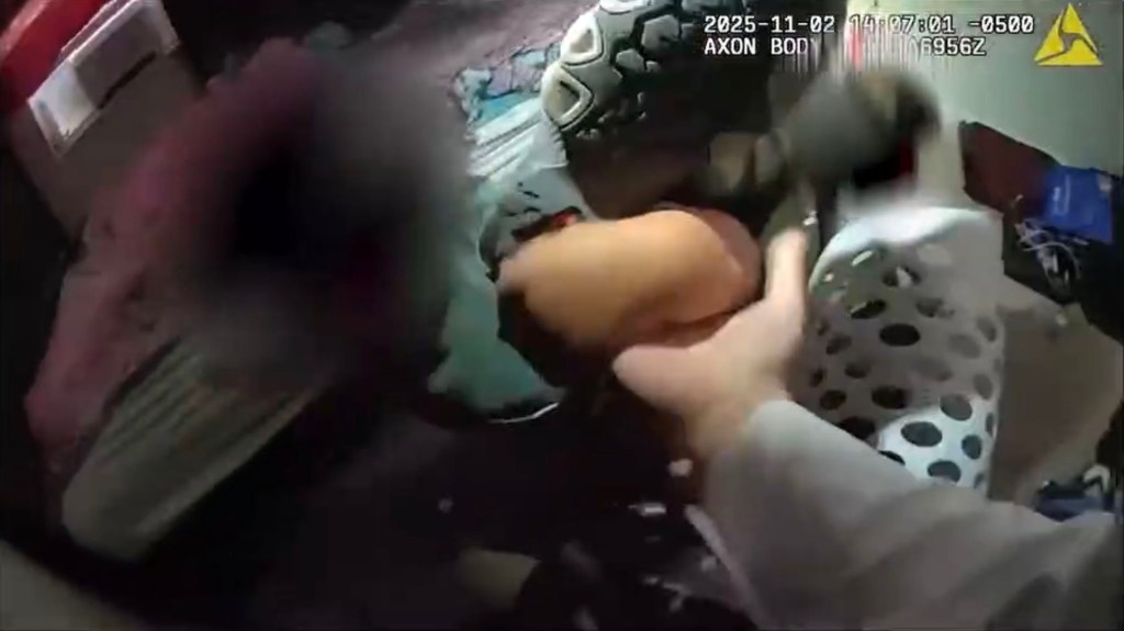 A bodycam view shows a person reaching for a white and black spotted item, with other items in the background.