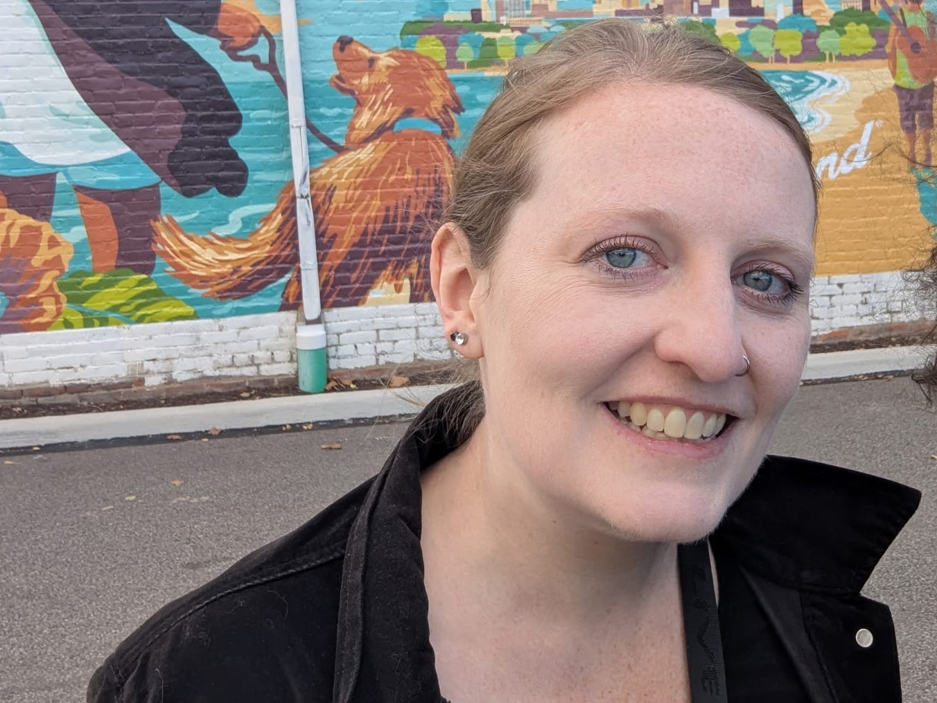 The author poses next to a mural outdoors.