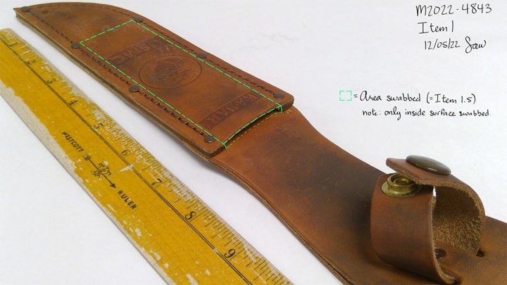 Brown leather Ka-Bar knife sheath next to a yellow ruler, with a green dotted outline indicating the swabbed area.