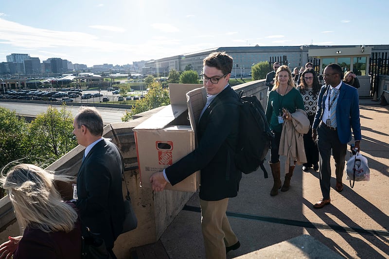 Jared Szuba of the Al-Monitor carries a box as reporters walk out together after turning in their credentials for refusing to sign new reporting limits dictated by Secretary of Defense Pete Hegseth, at the Pentagon on Wednesday, Oct 15, 2025 in Arlington, VA.