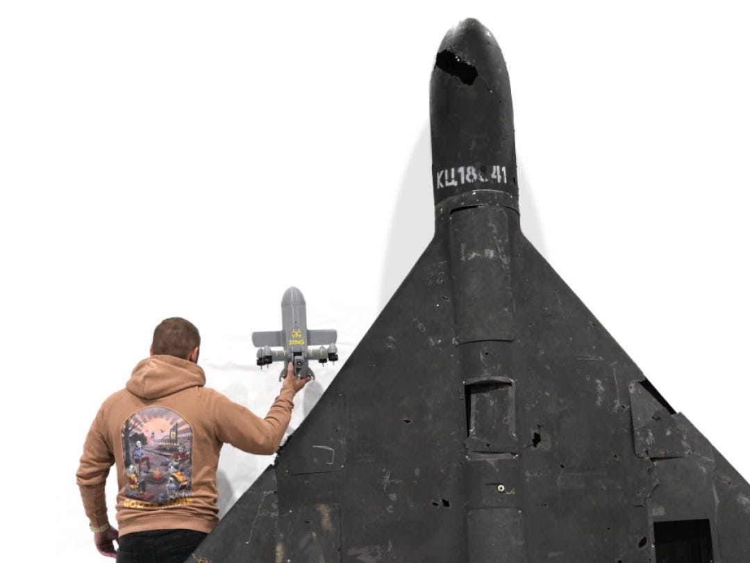 A man holds up the Sting for a size comparison with a downed Shahed drone.