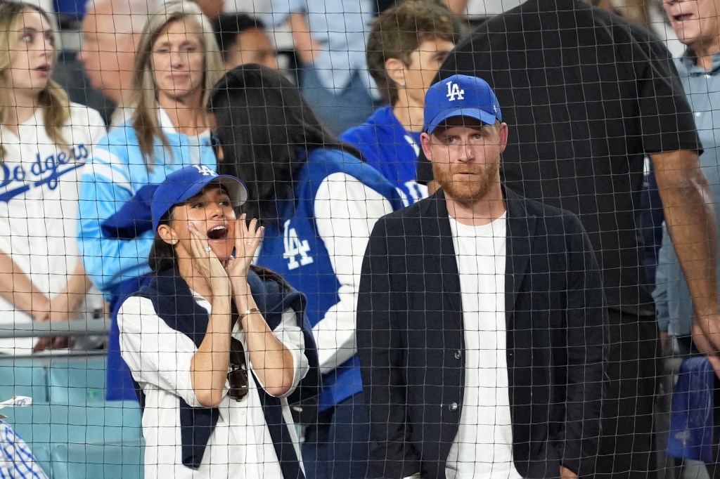 Prince Harry and Meghan Markle watching the 2025 MLB World Series, with Meghan holding her hands to her face in excitement.
