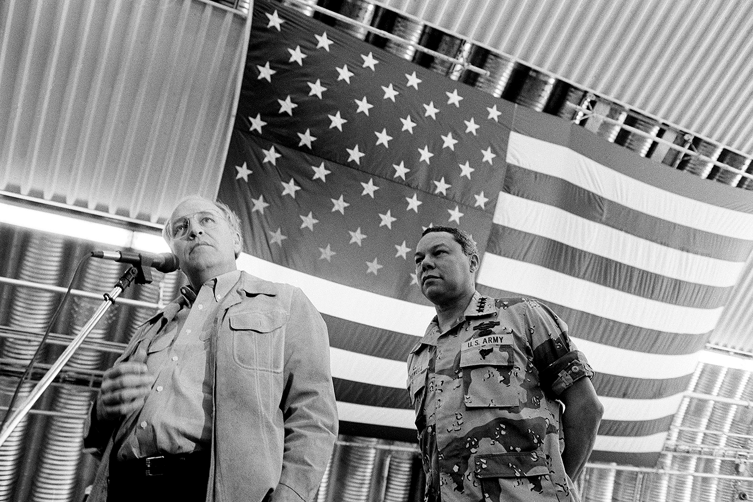 Dick Cheney and Colin Powell appear under a large American flag.