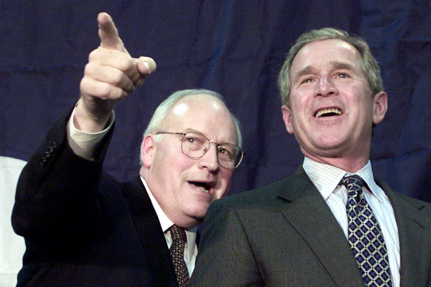Dick Cheney points and George W. Bush laughs.
