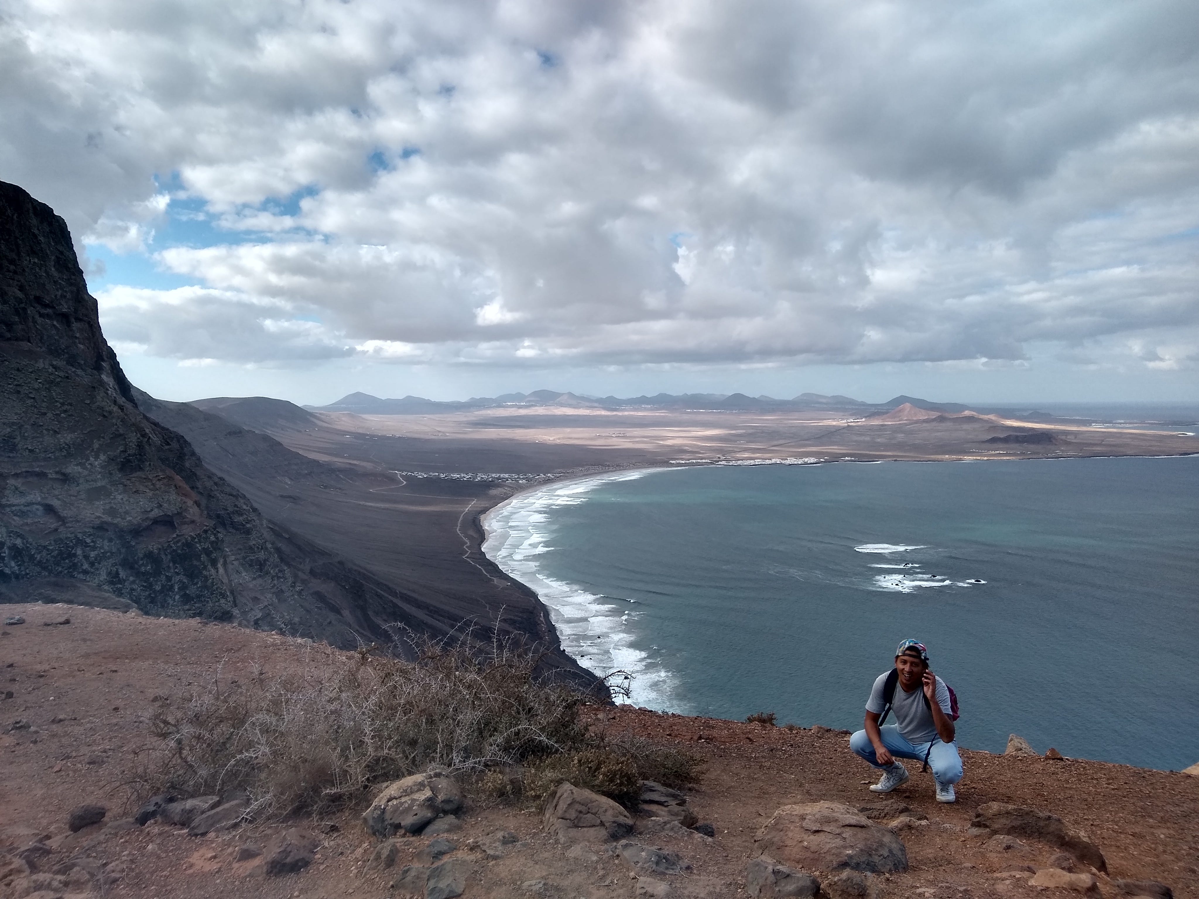 tino roco sitting in front of water on rock