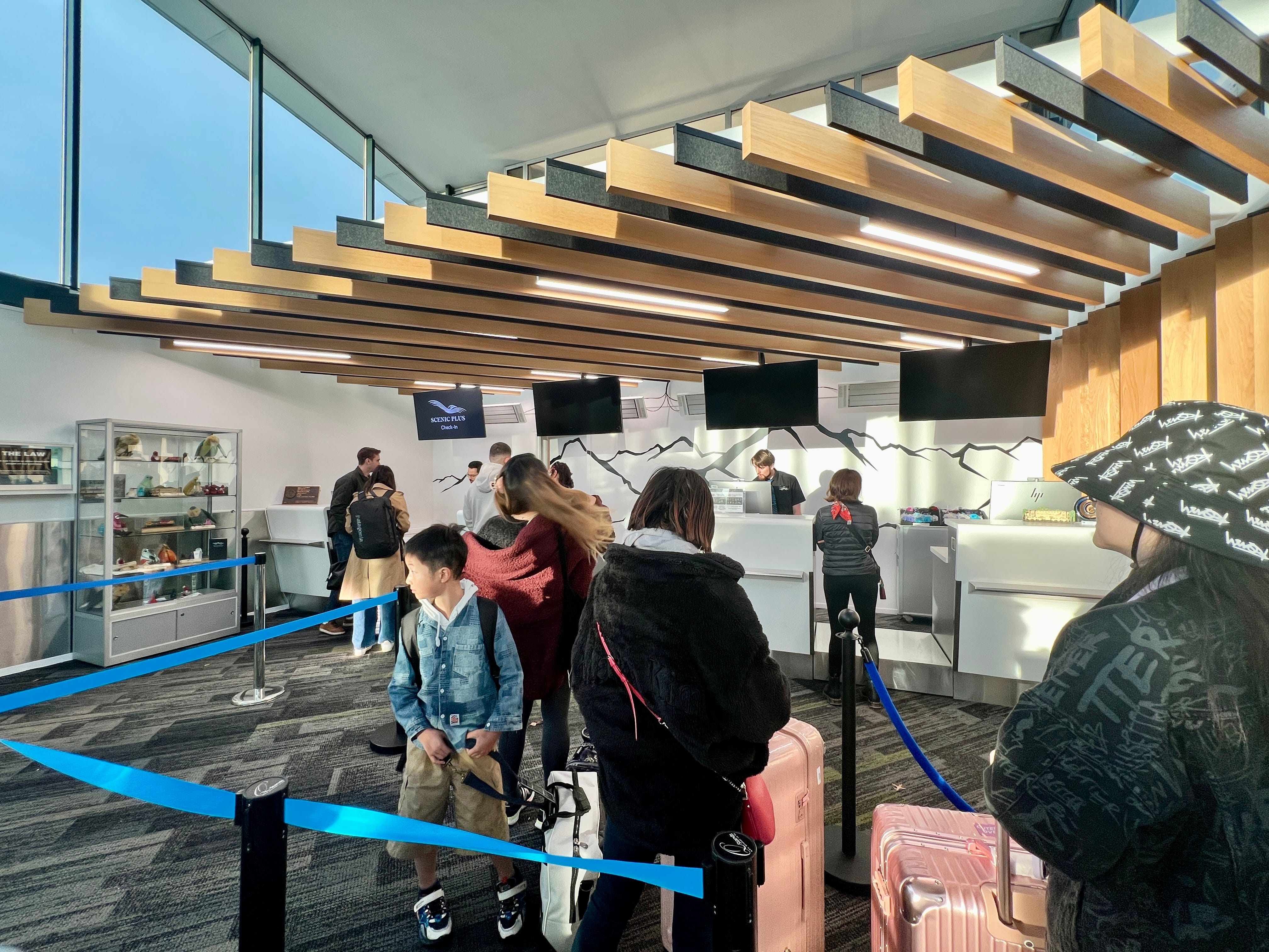 People waiting in line at TranzAlpine train station with suitcases