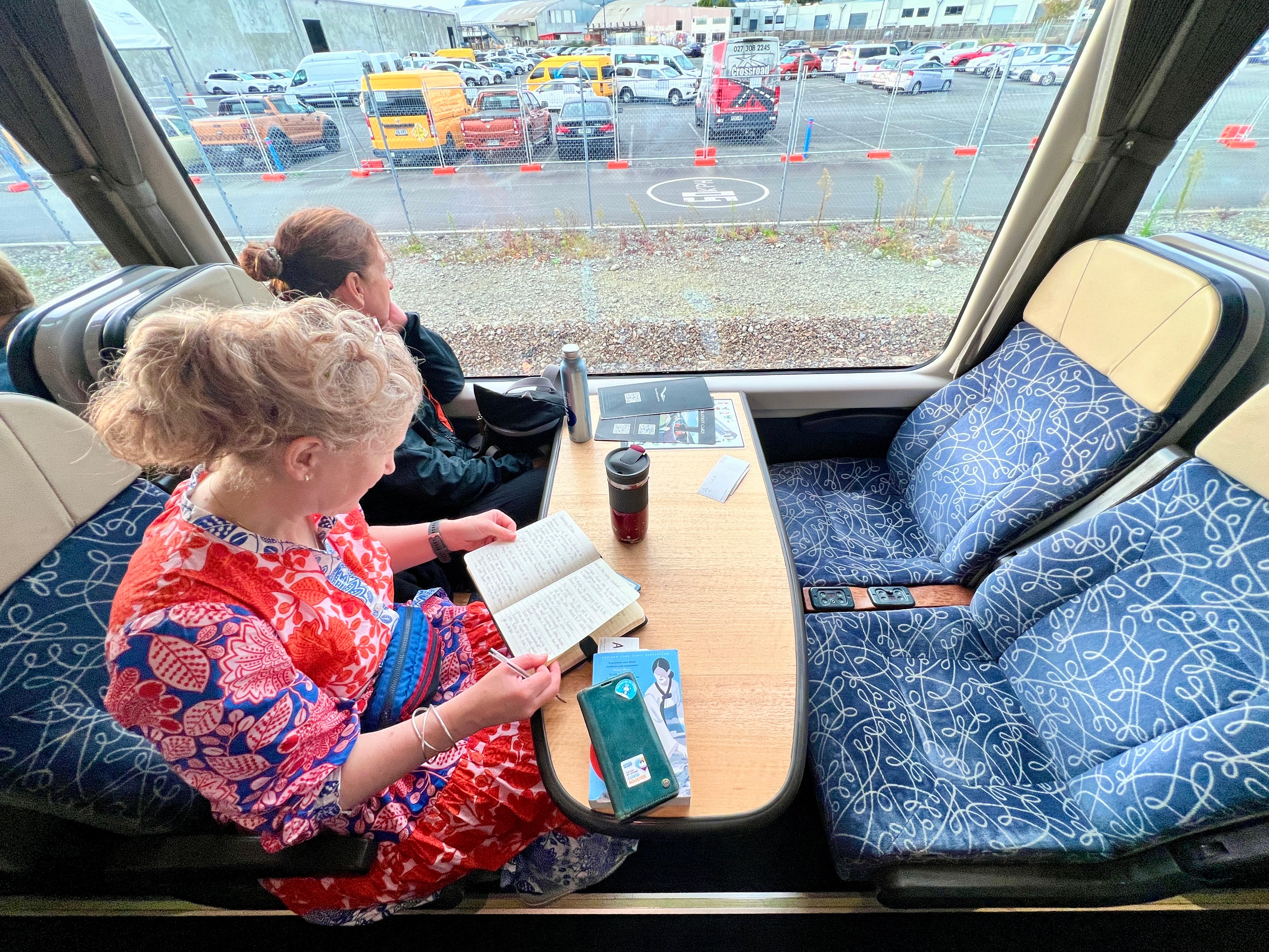People sitting, reading in train car while looking out of window