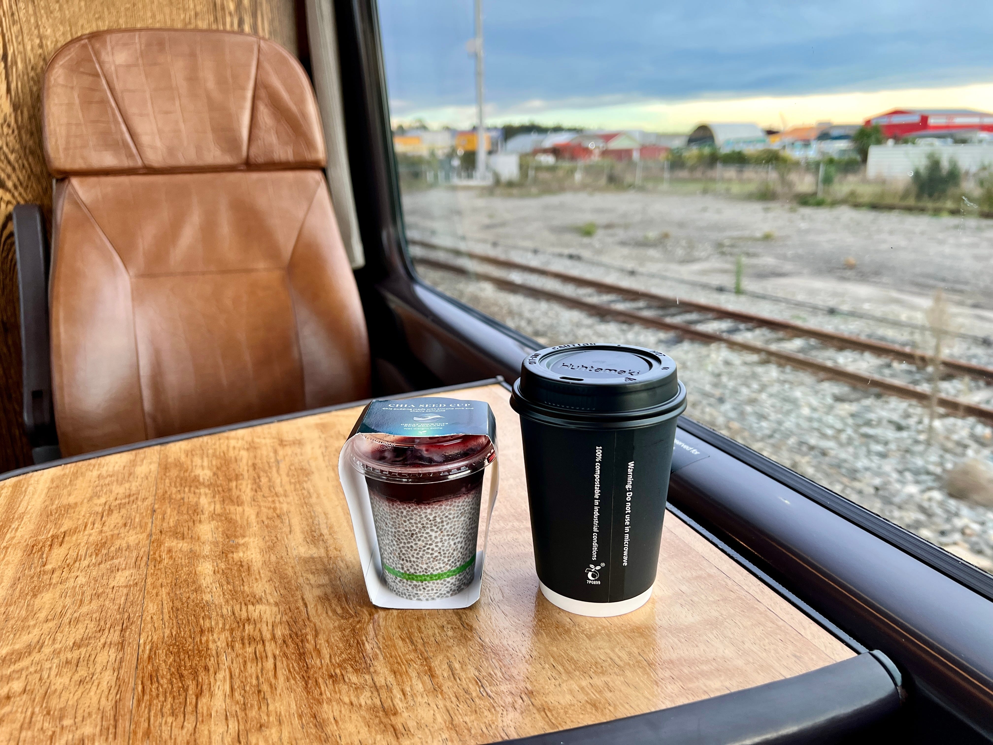 Coffee cup and chia pudding on table on train in front of window