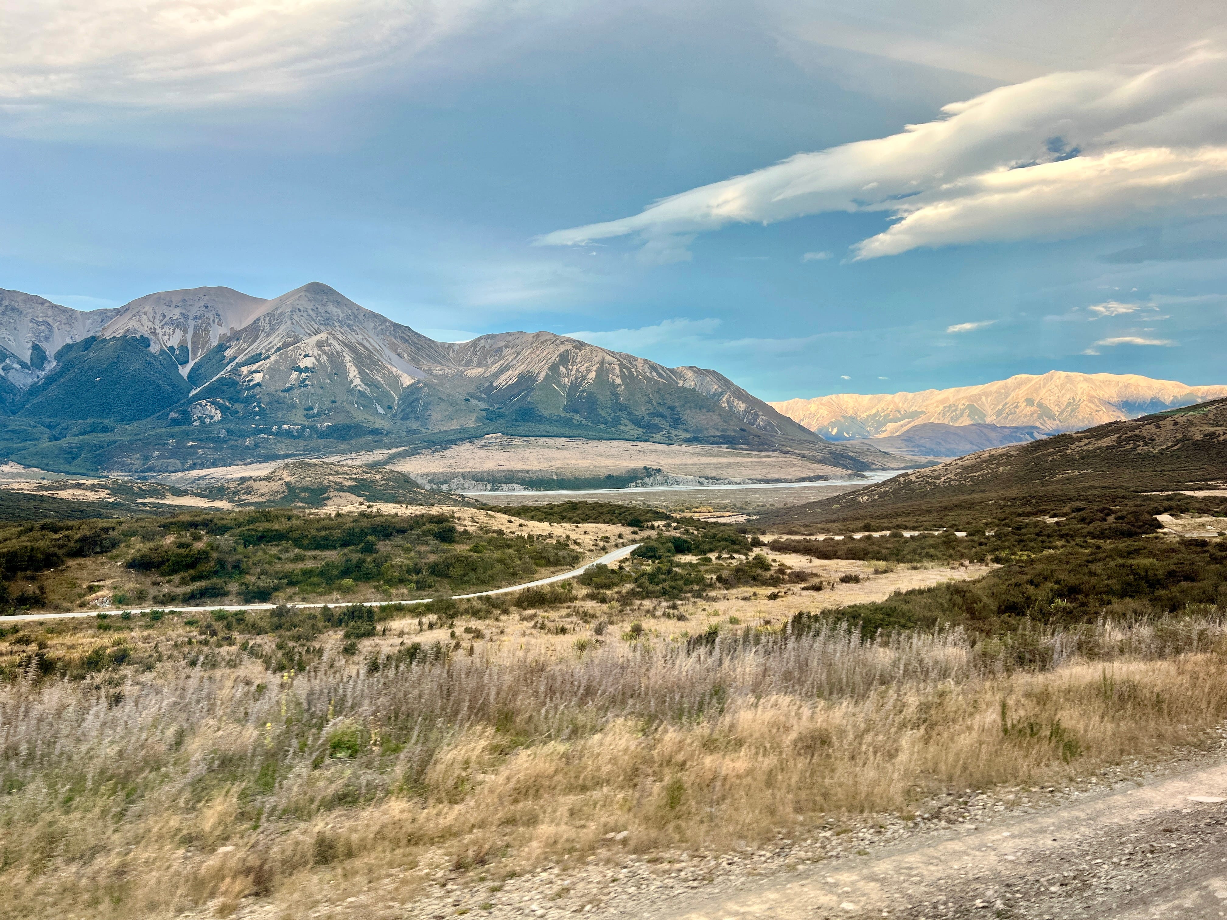 View of mountains, grass in New Zealand from train window
