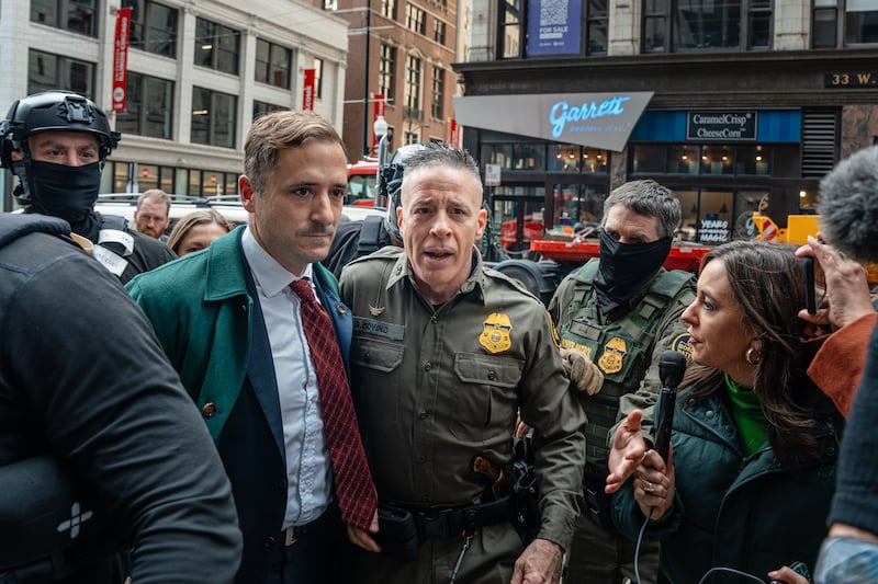 Border Patrol commander Gregory Bovino (C) pushes through a crowd of media and protesters as he enters the Dirksen Federal Building