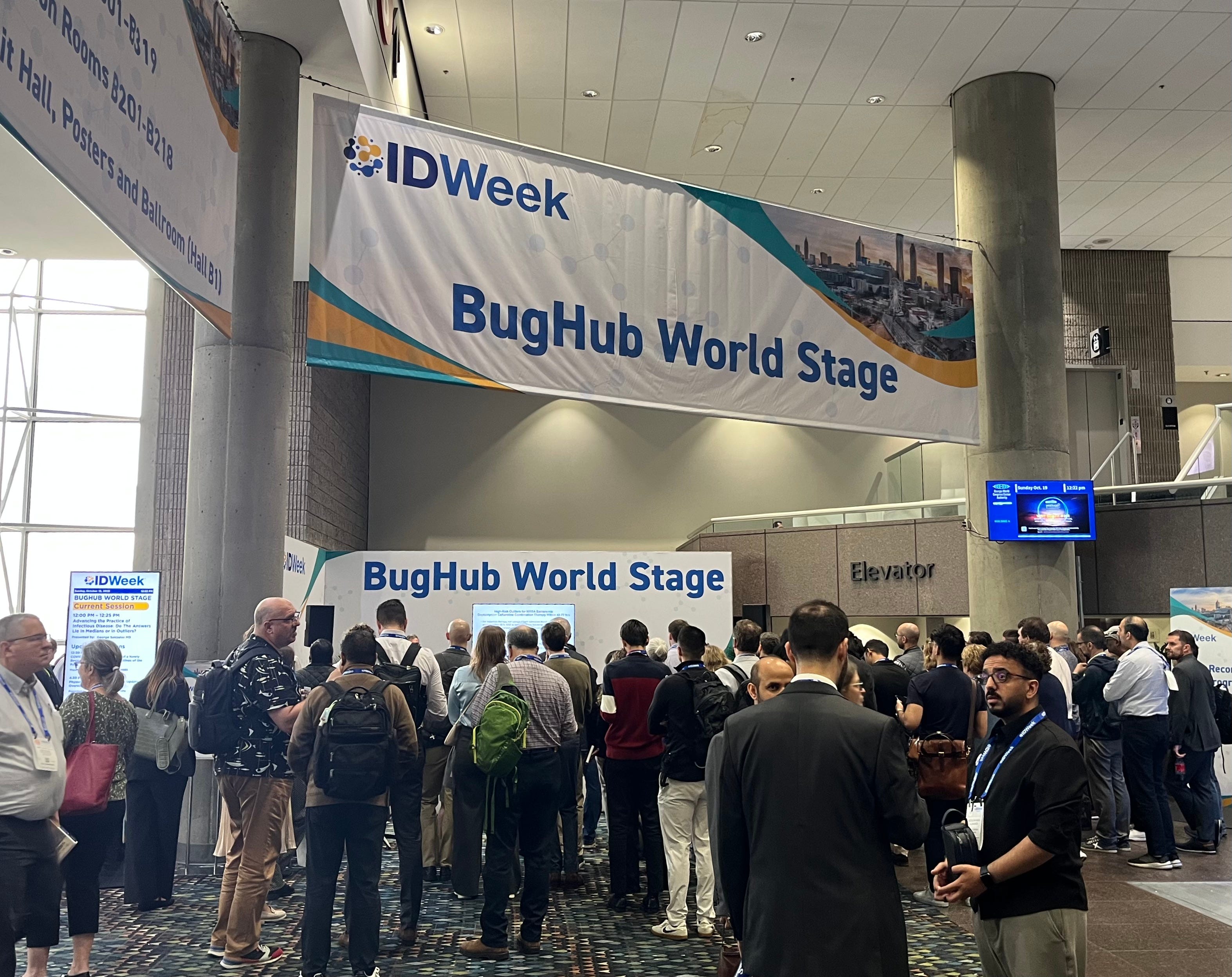 IDWeek attendees gather around the BugHub stage for a presentation.