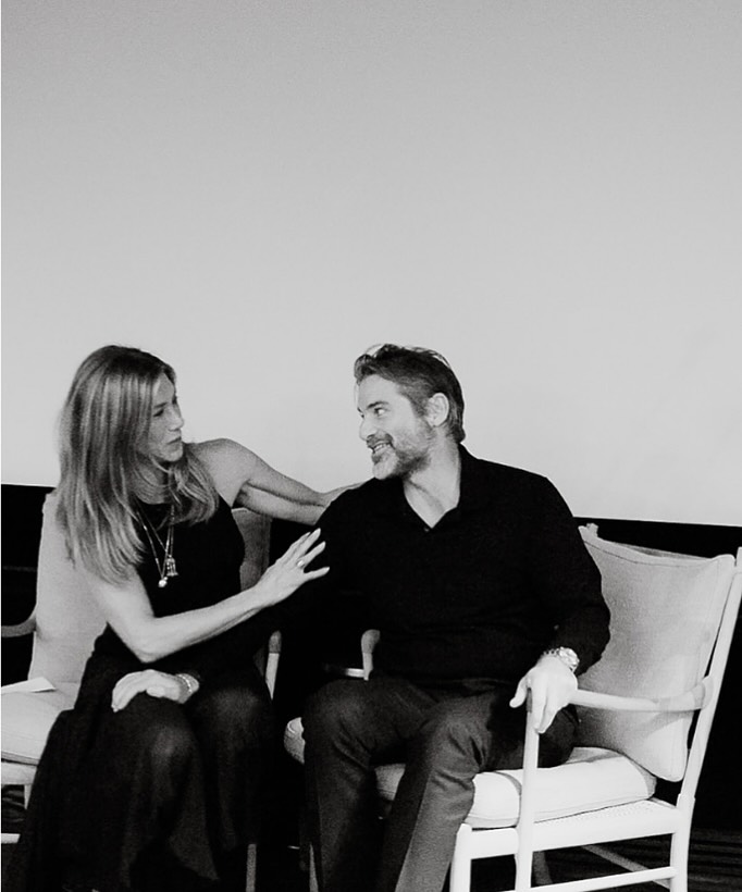 Jennifer Aniston looking affectionately at Jim Curtis while sitting with her arm around him.