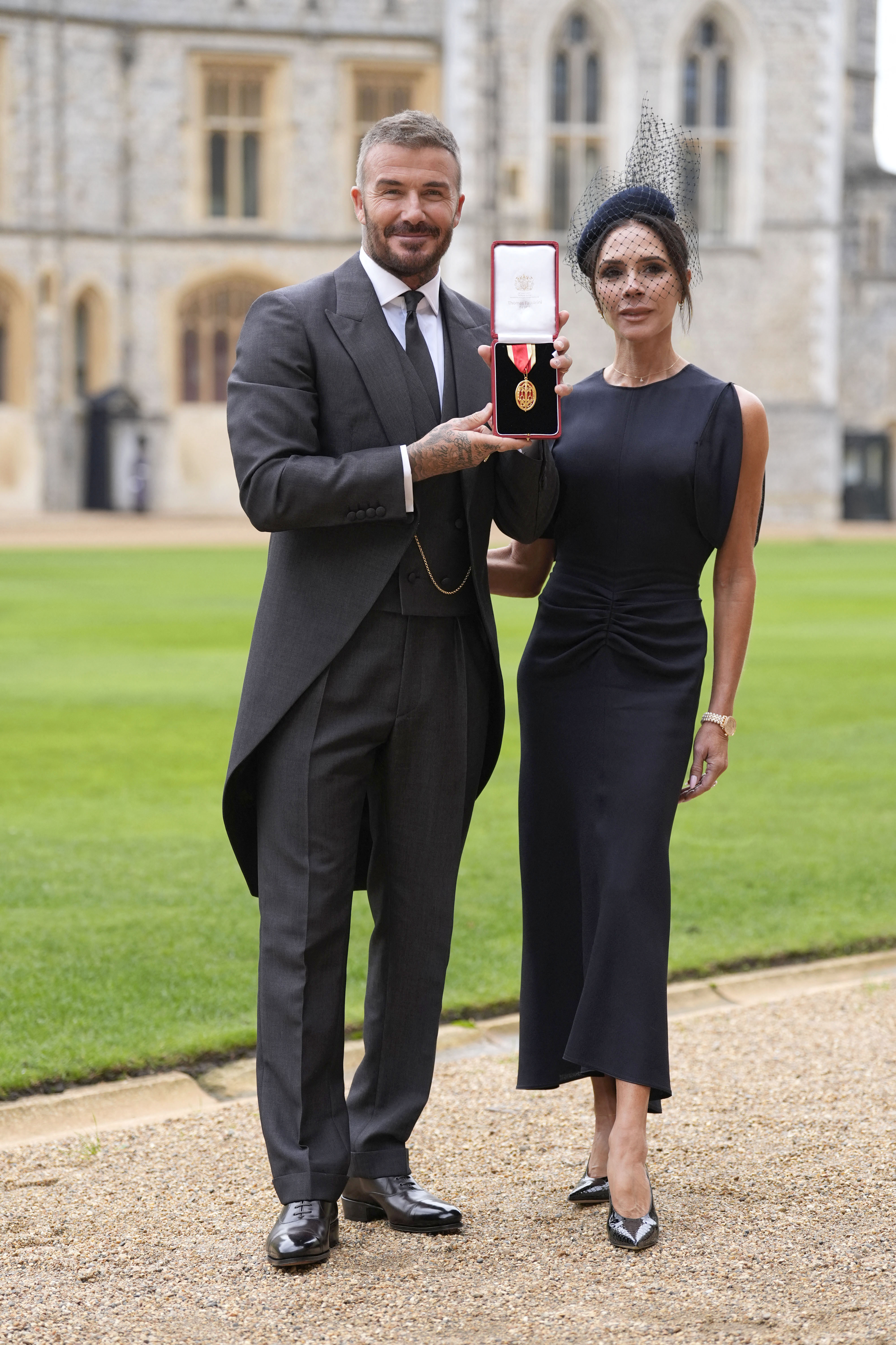 Former England footballer David Beckham (L) poses next to his wife singer and fashion designer Victoria Beckham (R) with his medal after being appointed as a Knight Bachelor (Knighthood) for services to sport and charity at an investiture ceremony at Windsor Castle.