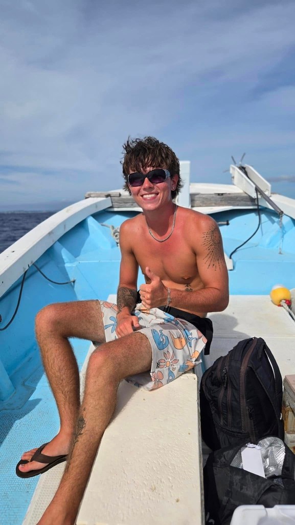 Owen Tillman Kenney, a 19-year-old college student, smiling and giving a thumbs up from inside a small boat.