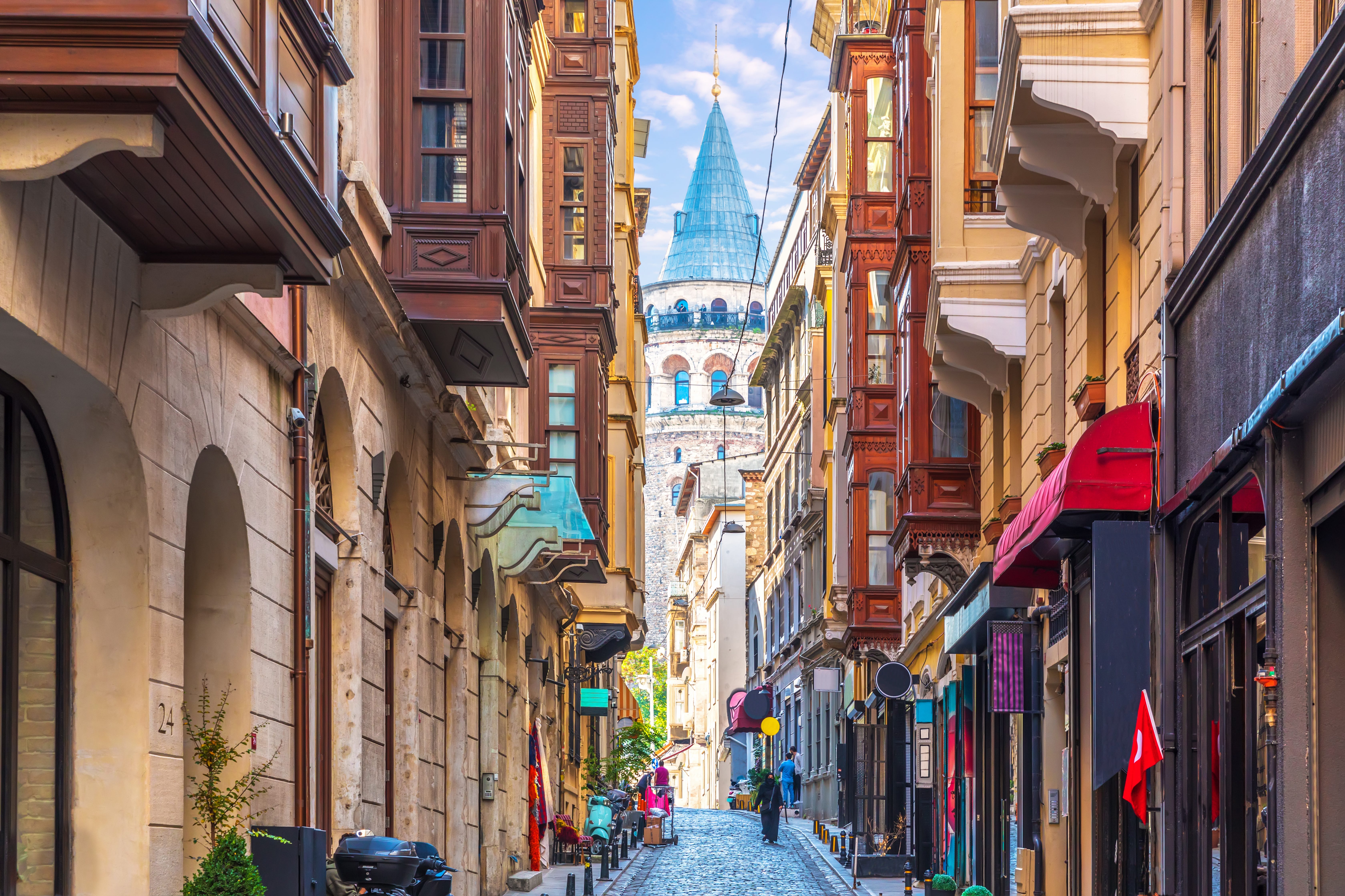 A narrow cobblestone street in Istanbul with the Galata Tower in the background.