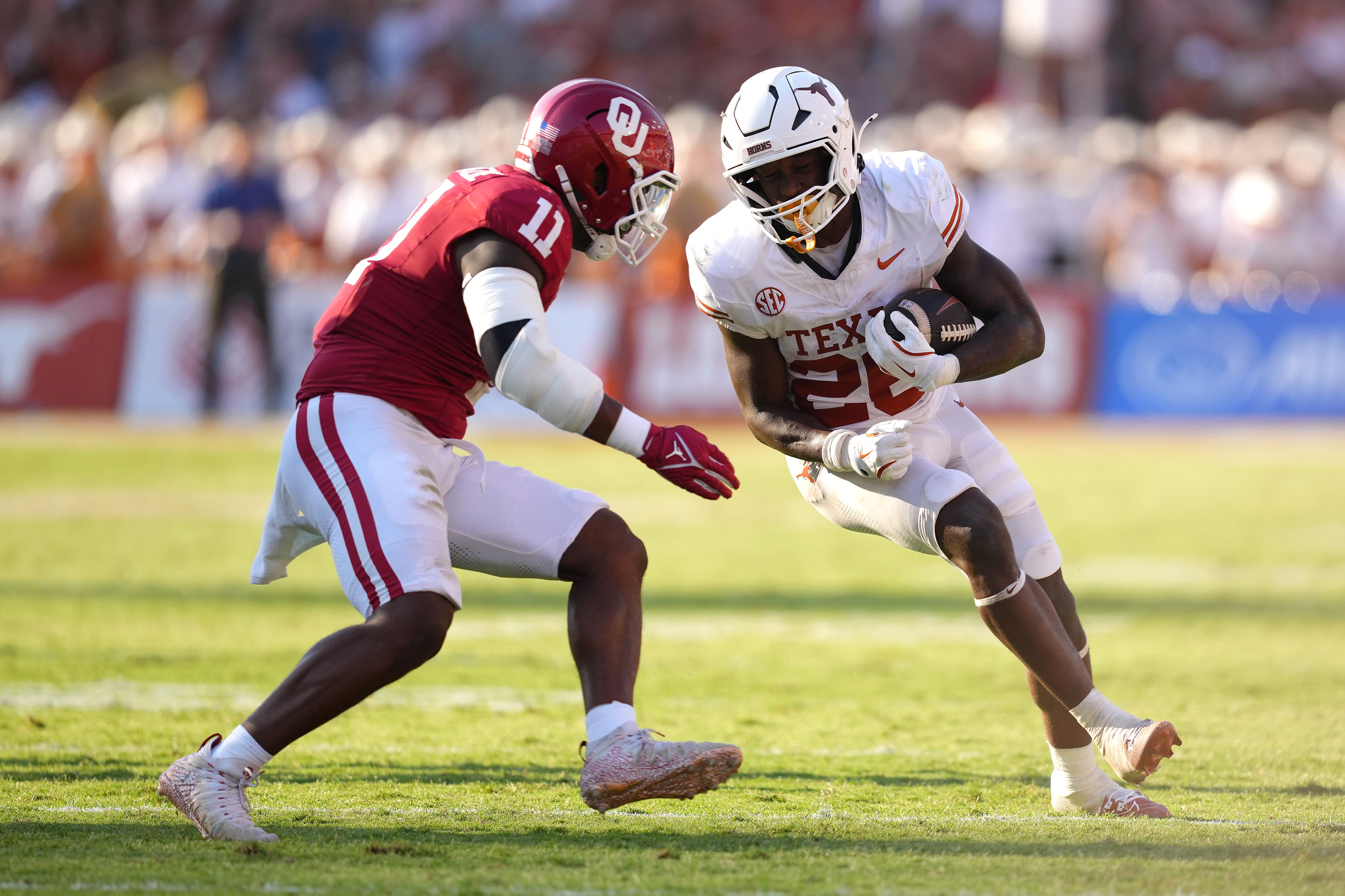 Quintrevion Wisner #26 of the Texas Longhorns runs the ball against an Oklahoma Sooners defender during a 2024 game.